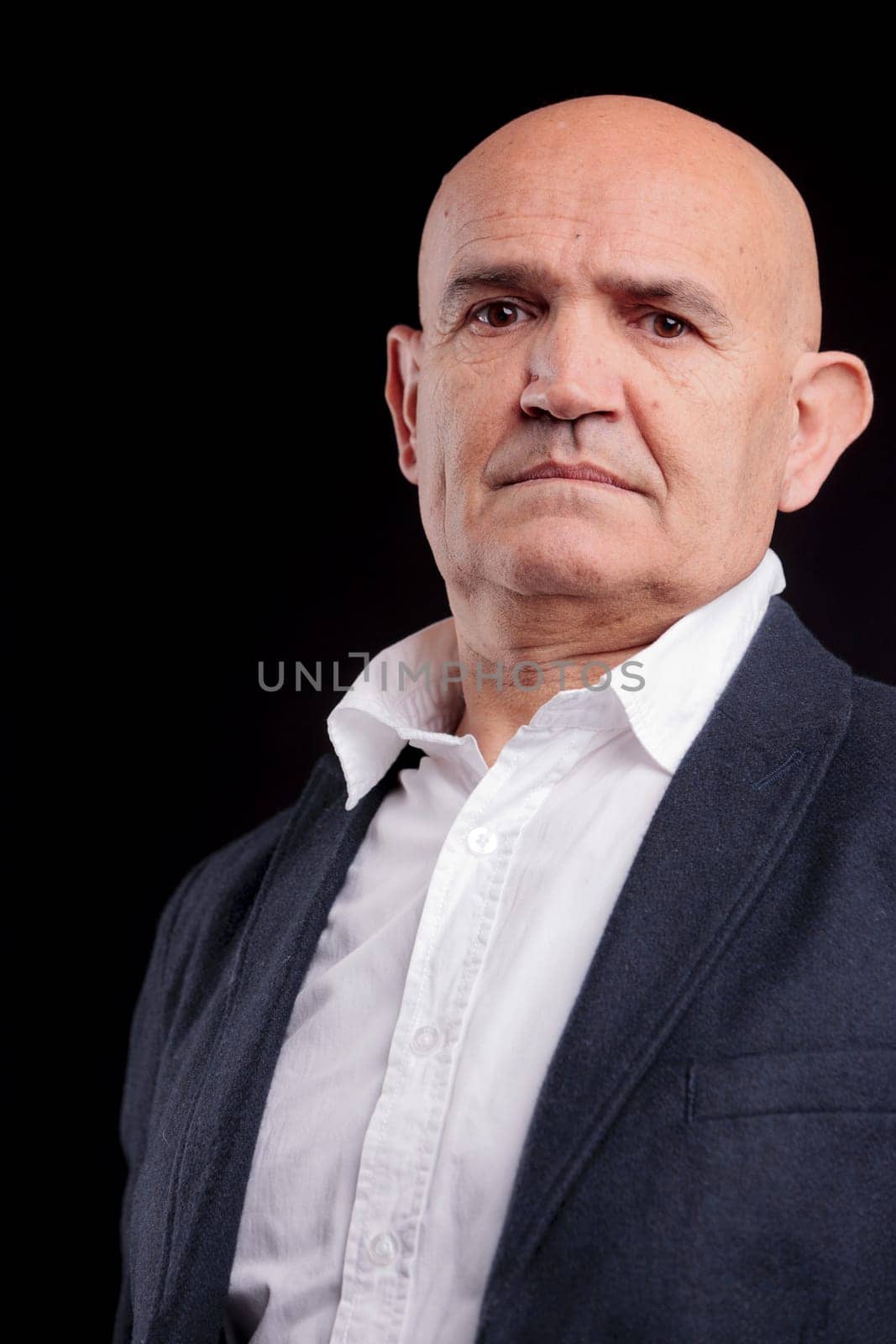 old bald self-confident businessman on a dark background