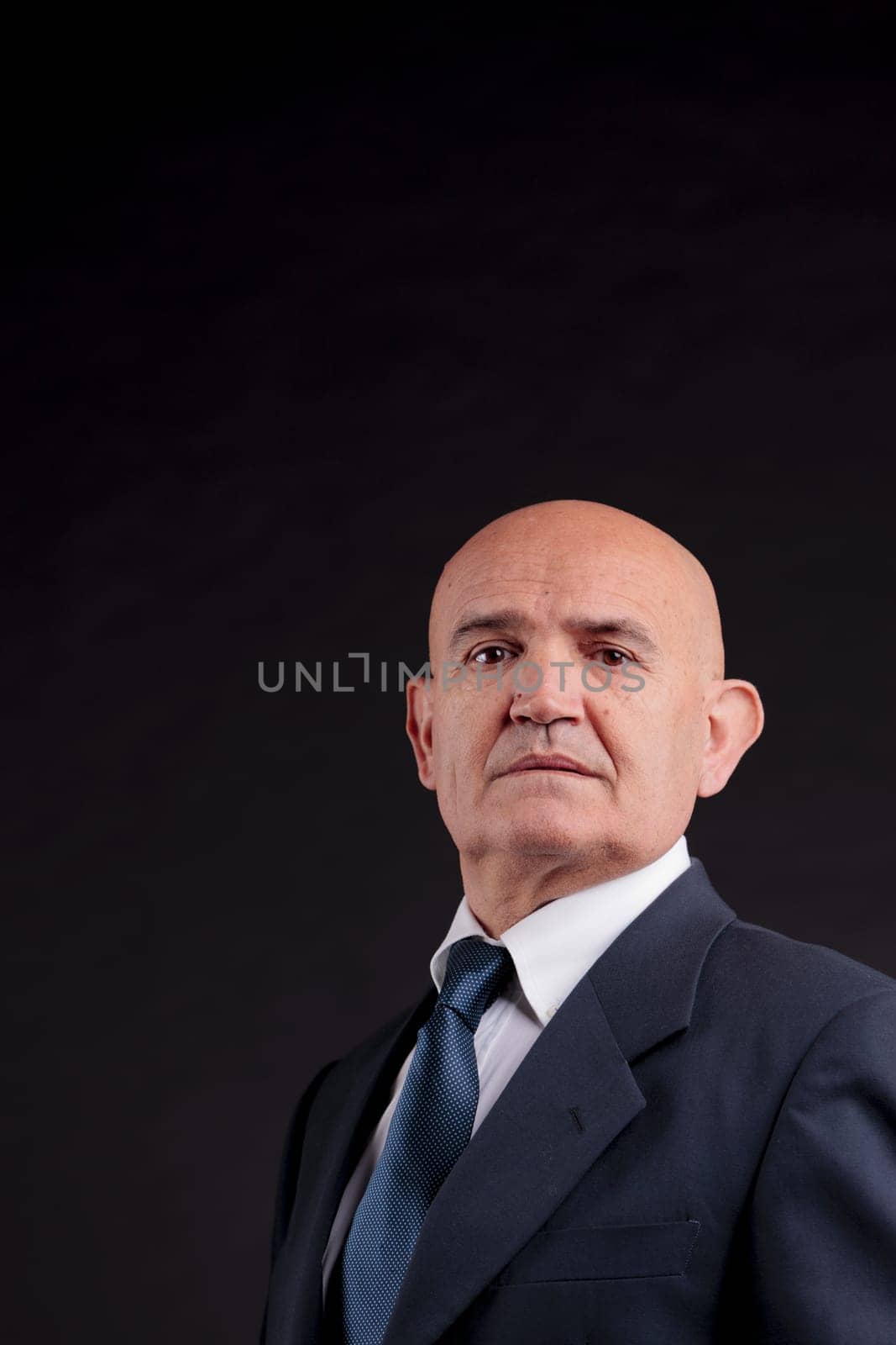 old bald self-confident businessman on a dark background