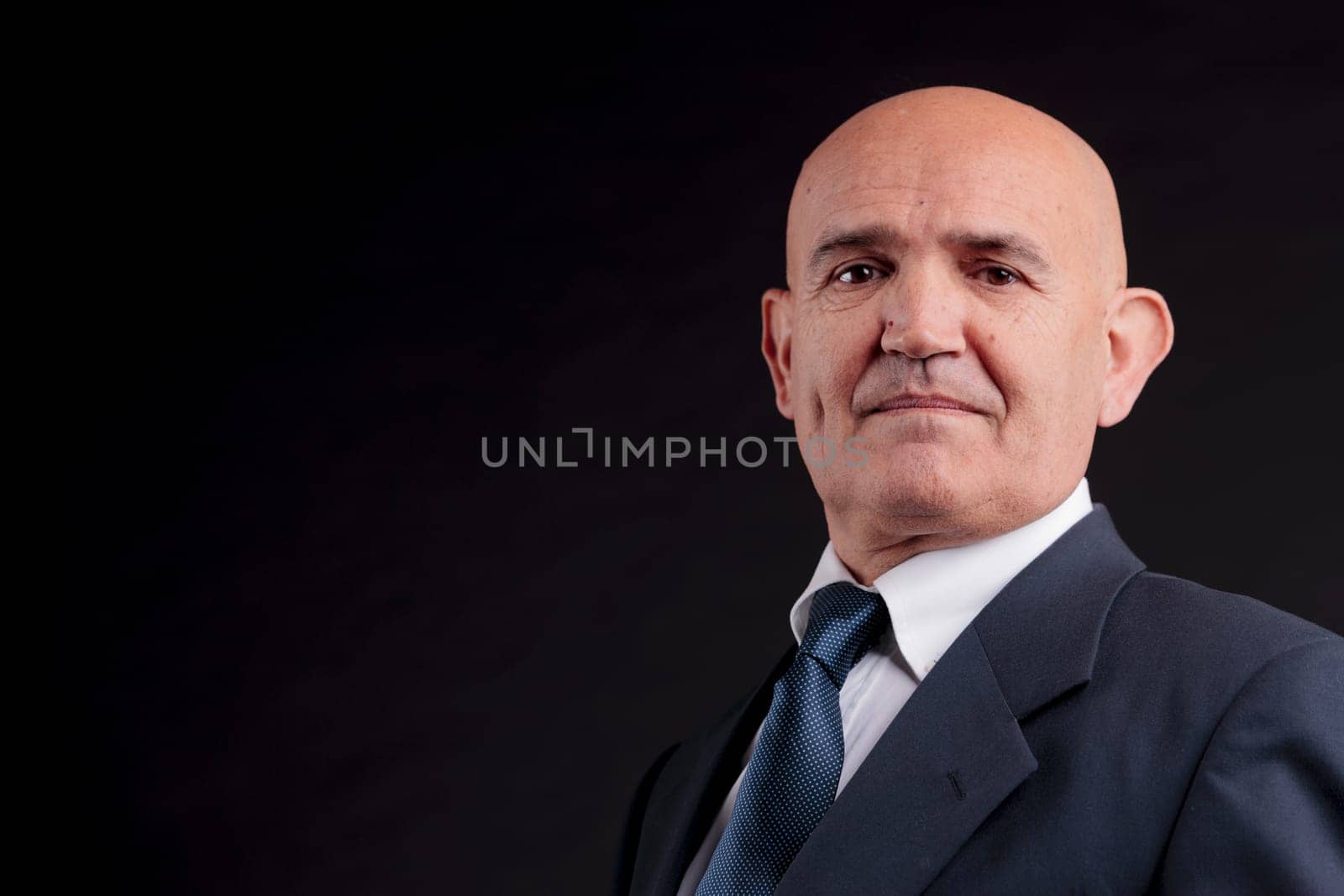 old bald self-confident businessman on a dark background