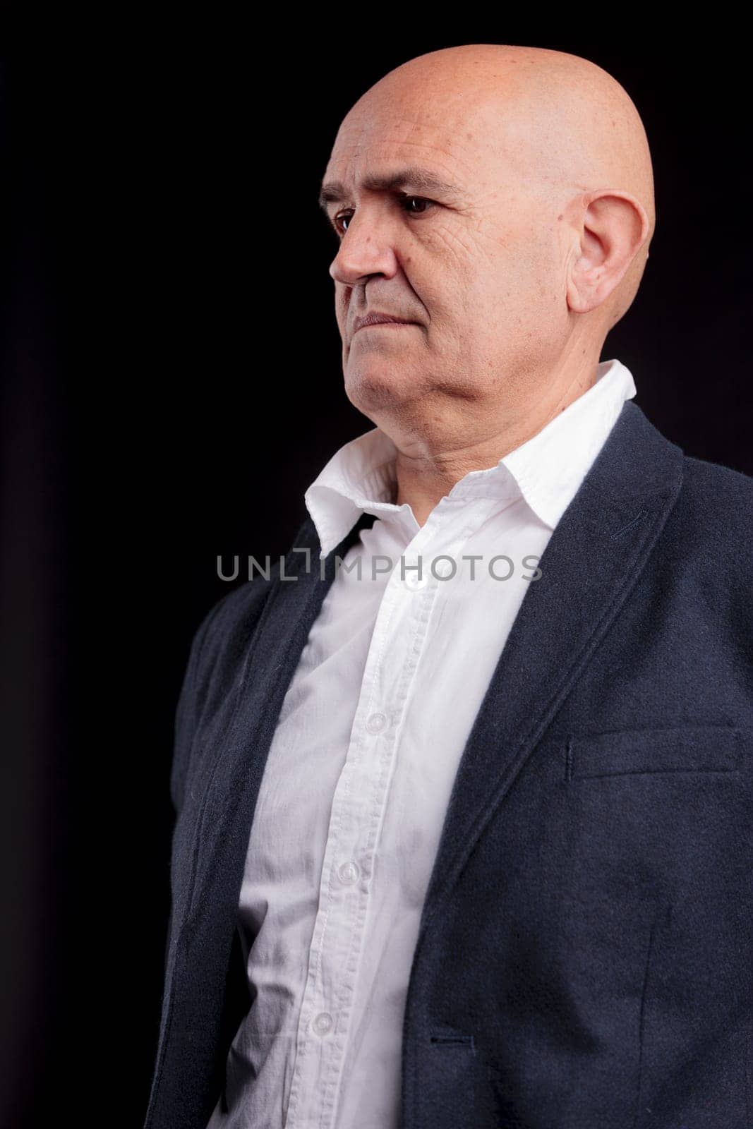 old bald self-confident businessman on a dark background