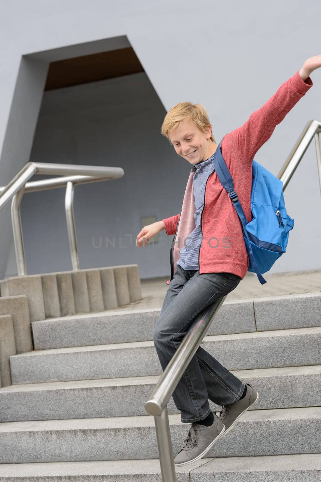 Excited teenage student sliding down handrail on school stairway