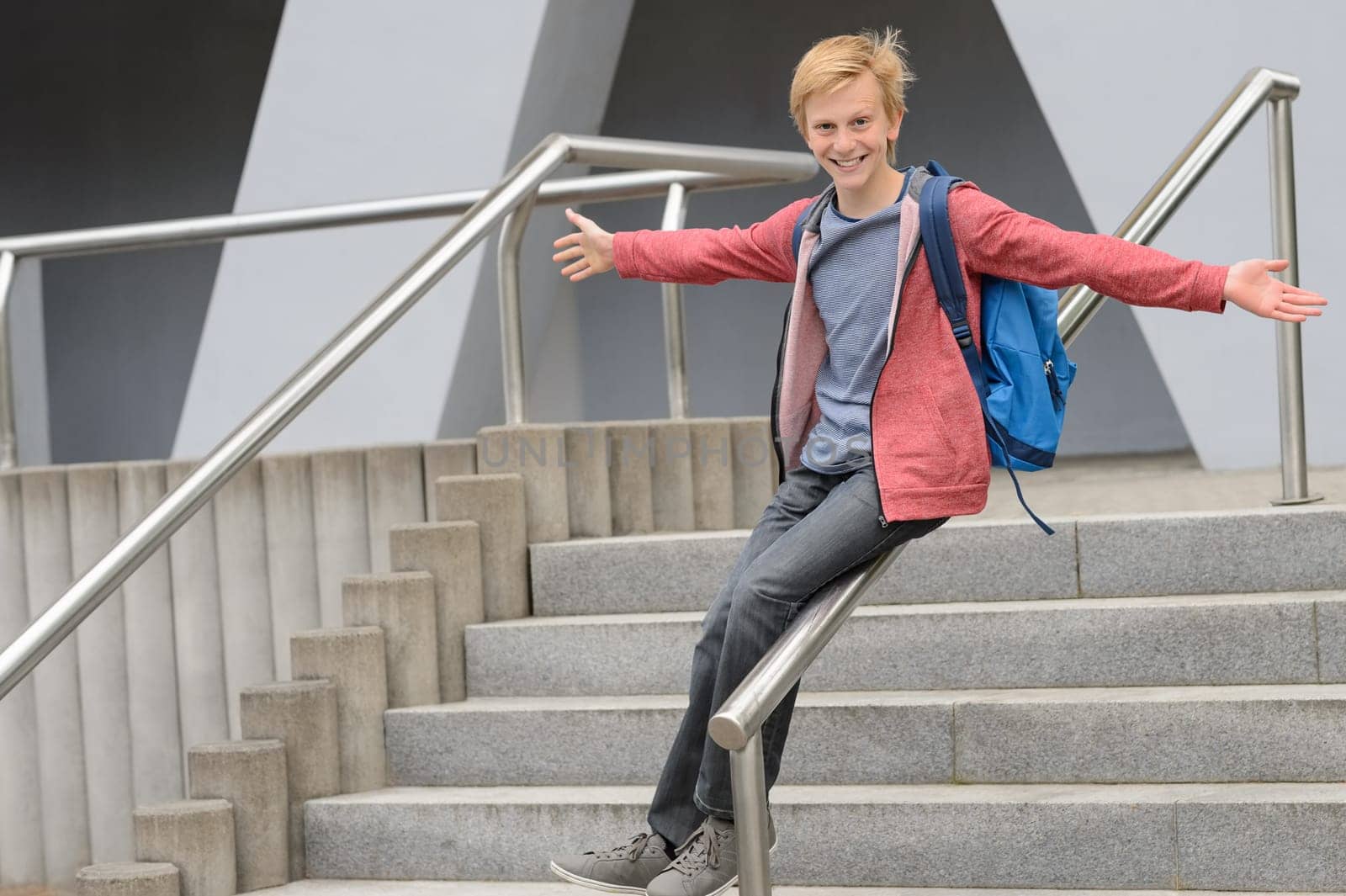 Playful teenage student sliding down railing on school stairway