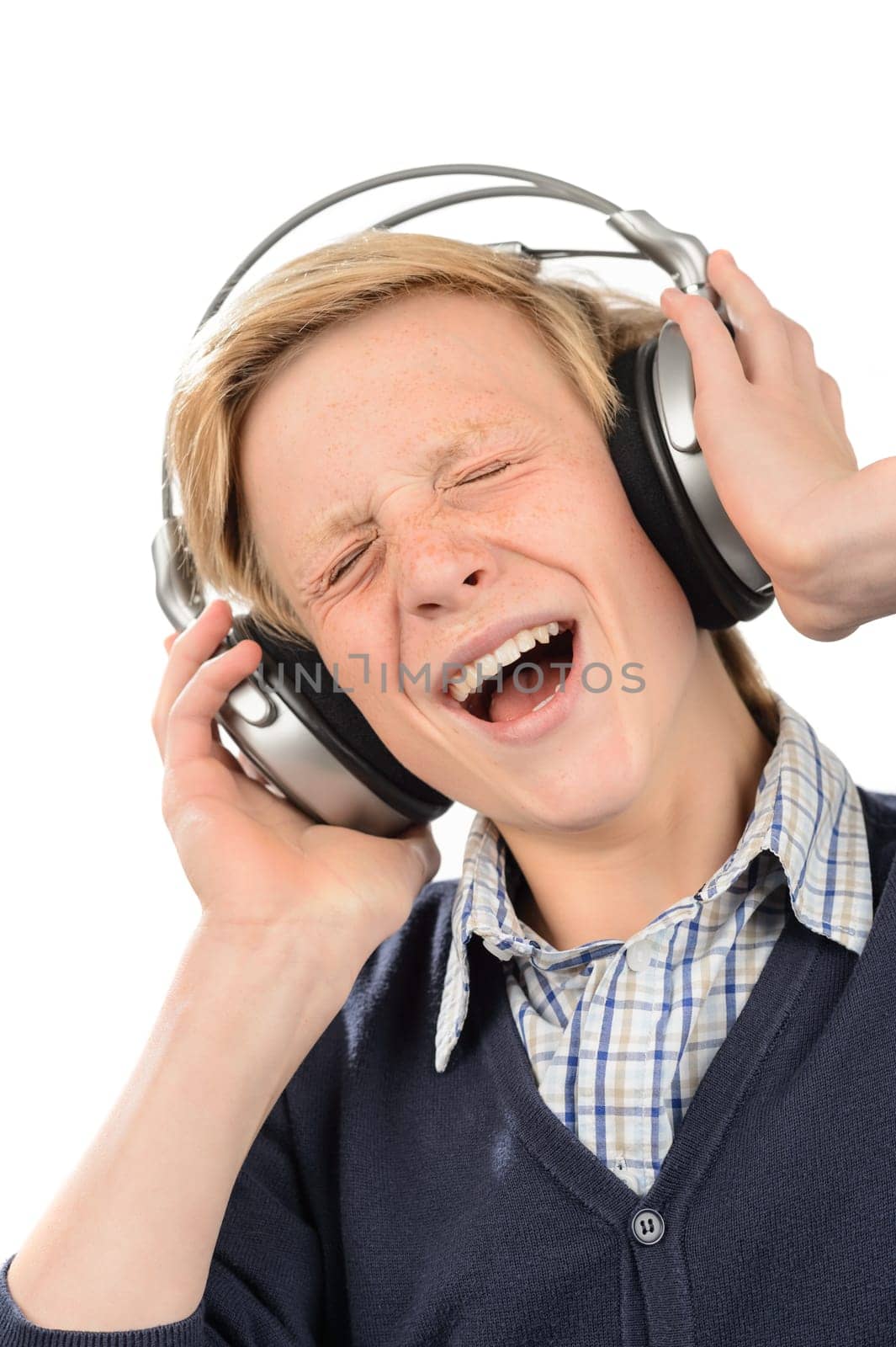 Cheerful teenage boy singing while enjoying music from headphones isolated