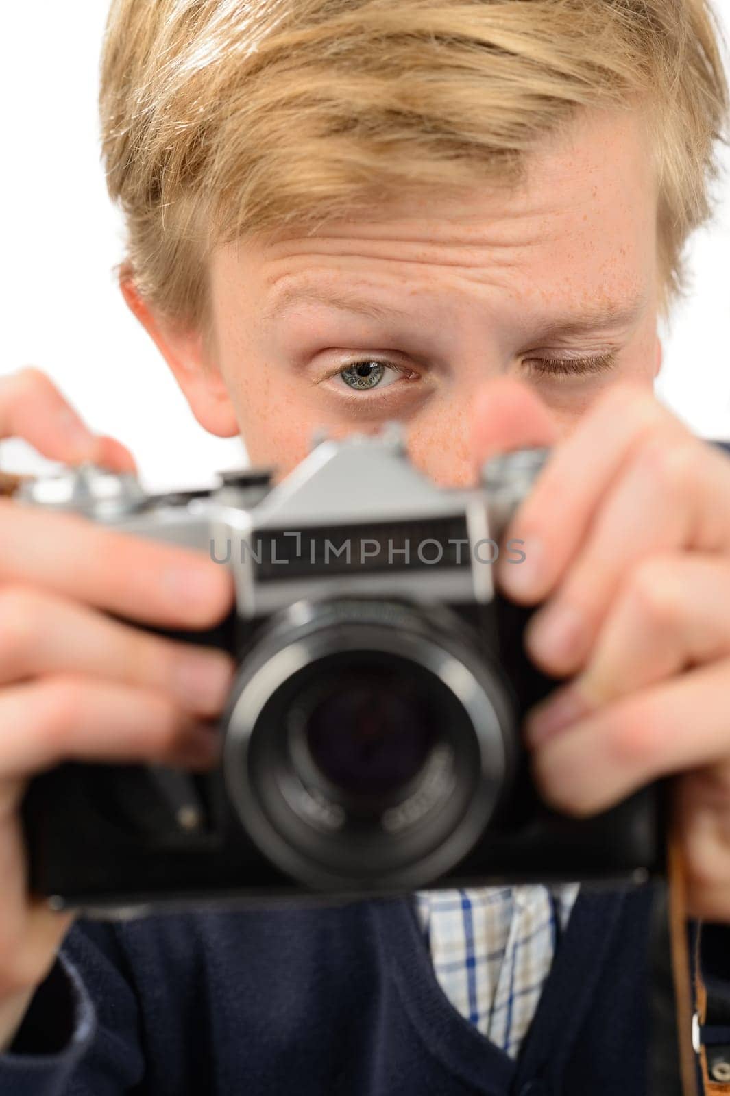 Teenage boy photographing through retro camera against white background