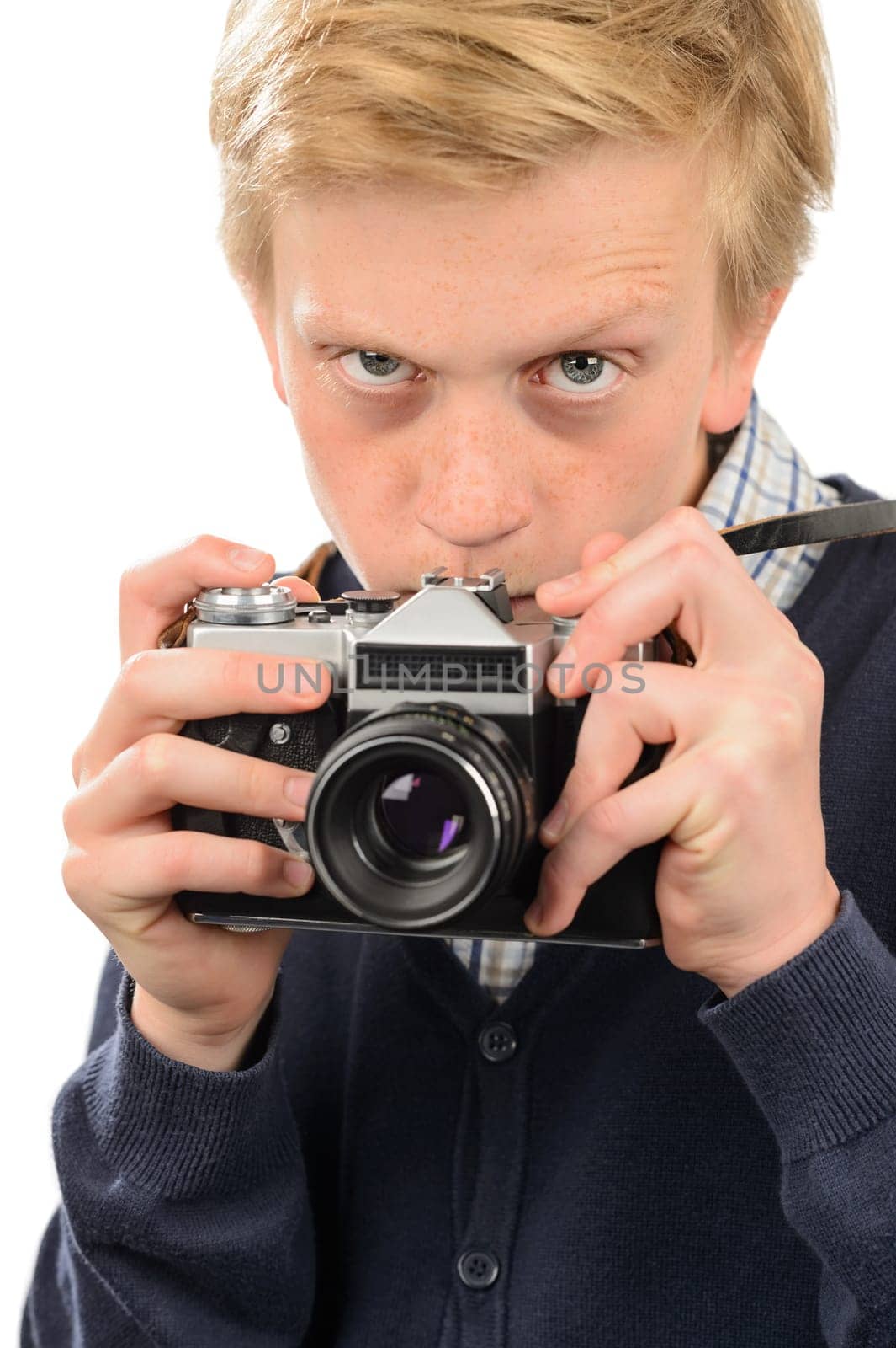 Suspicious teenage boy photographing through retro camera over white background