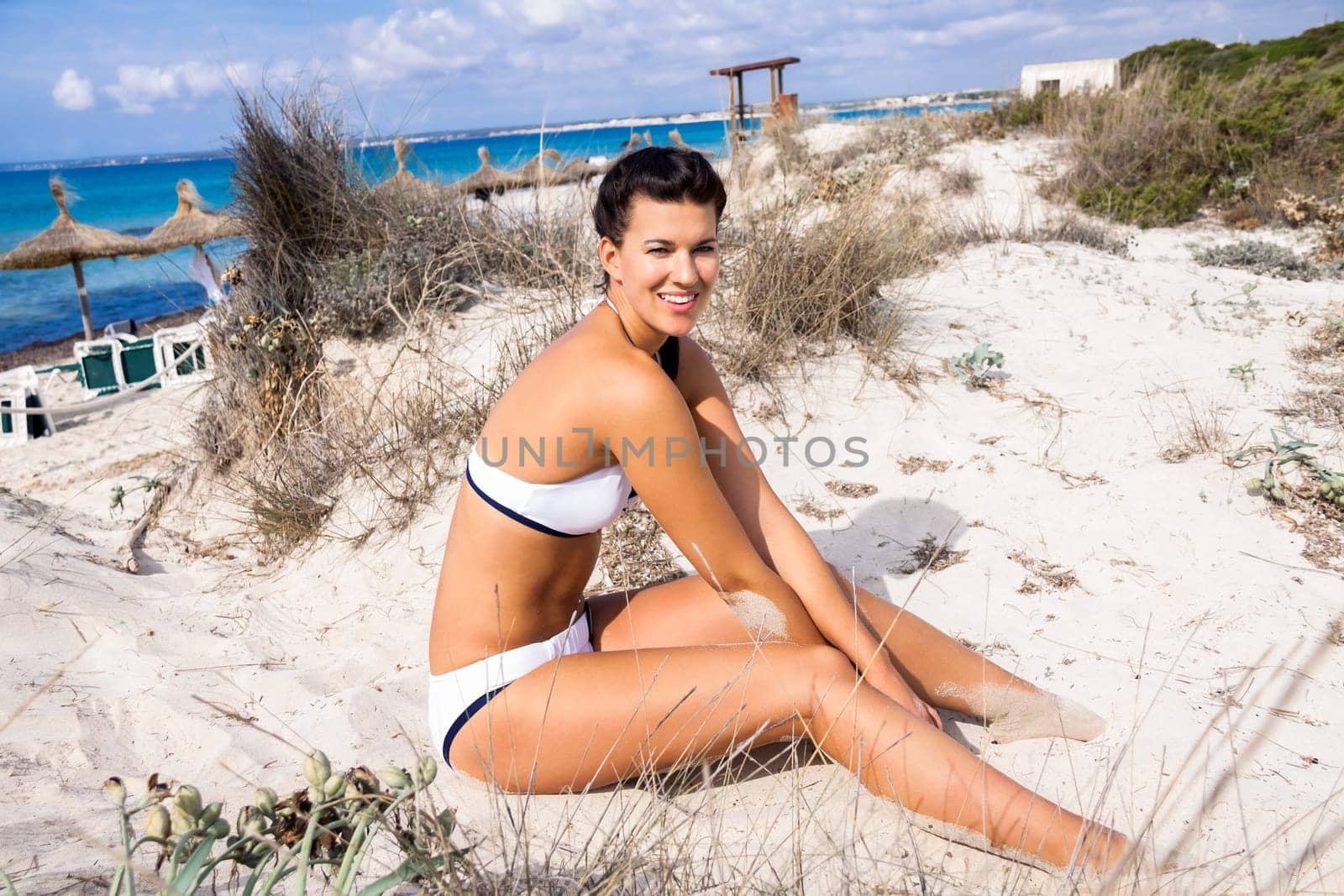 Young attractive woman in bikini in summer on the beach on vacation with blue hommel