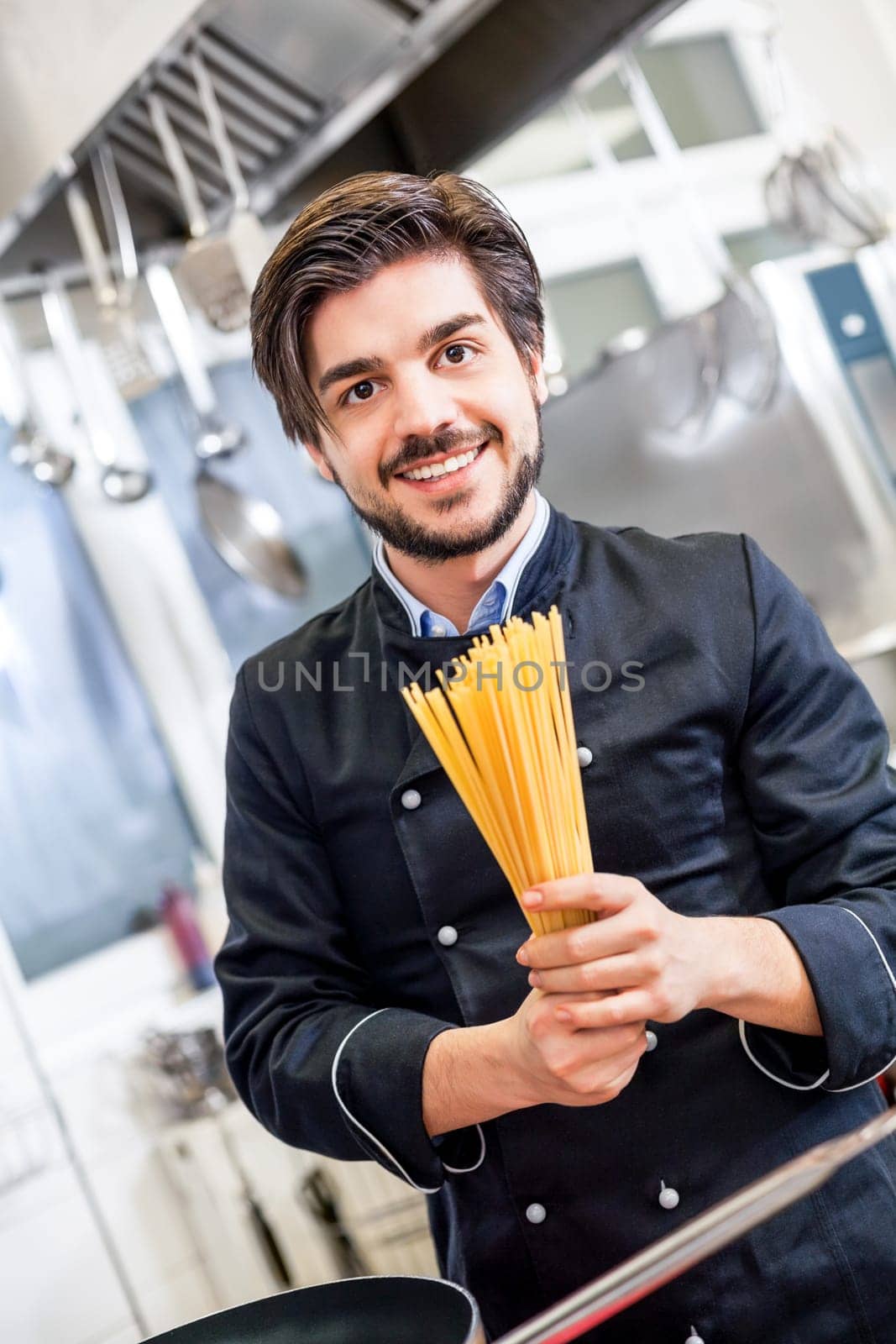 young chef prepares fresh Italian pasta spaghetti at the herd in the restaurant kitchen too