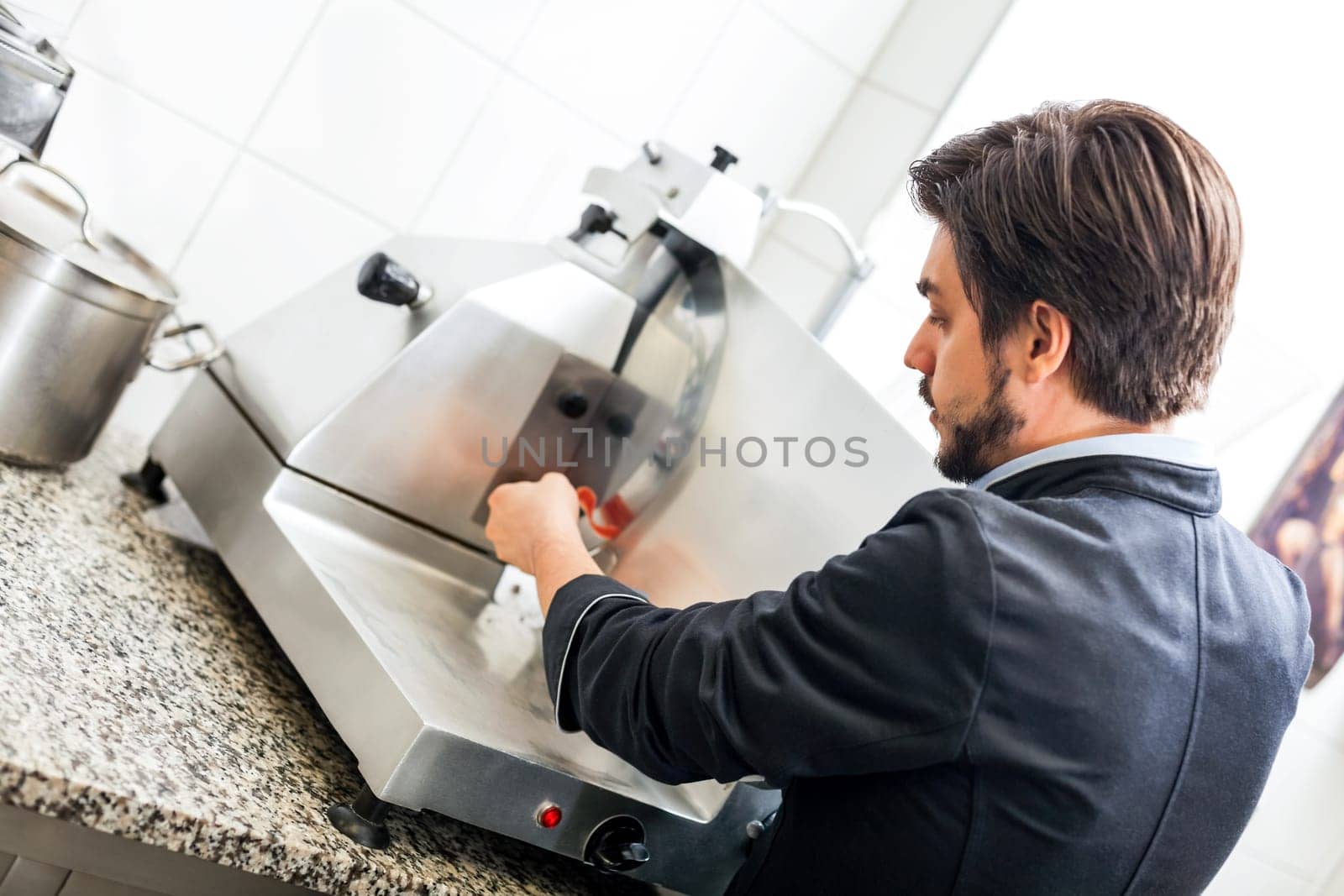 chef cuts fresh ham on the cutting machine in the restaurant kitchen