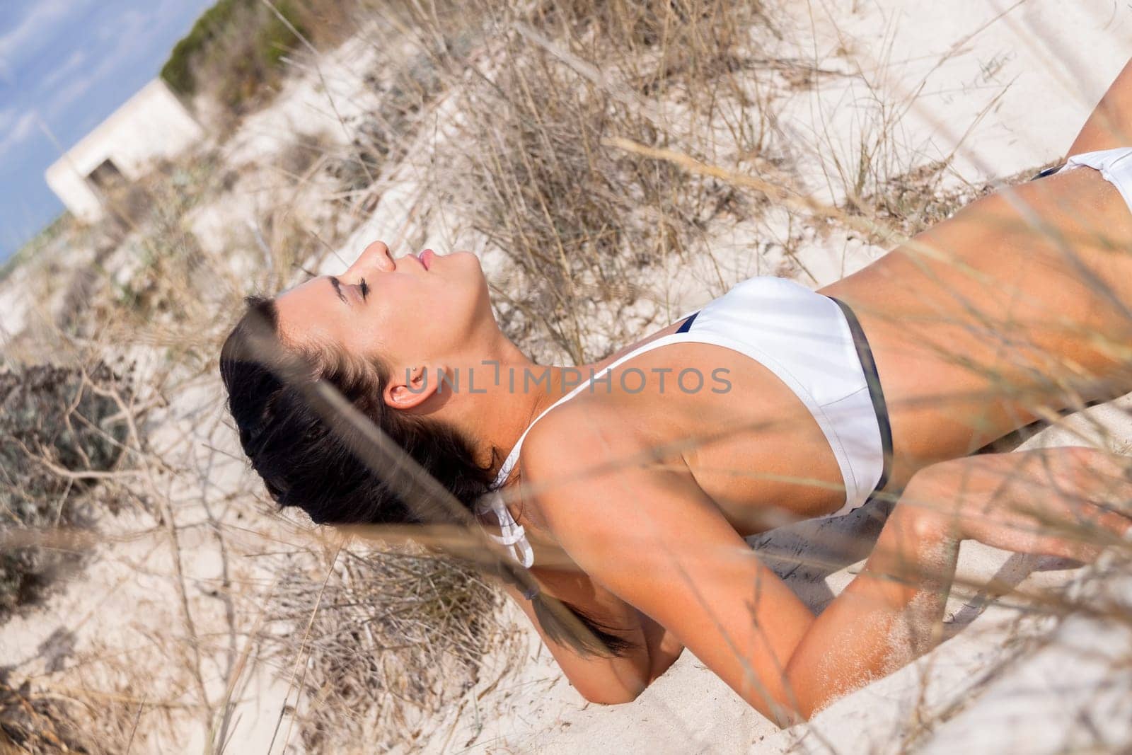 Young attractive woman in bikini in summer on the beach on vacation with blue hommel