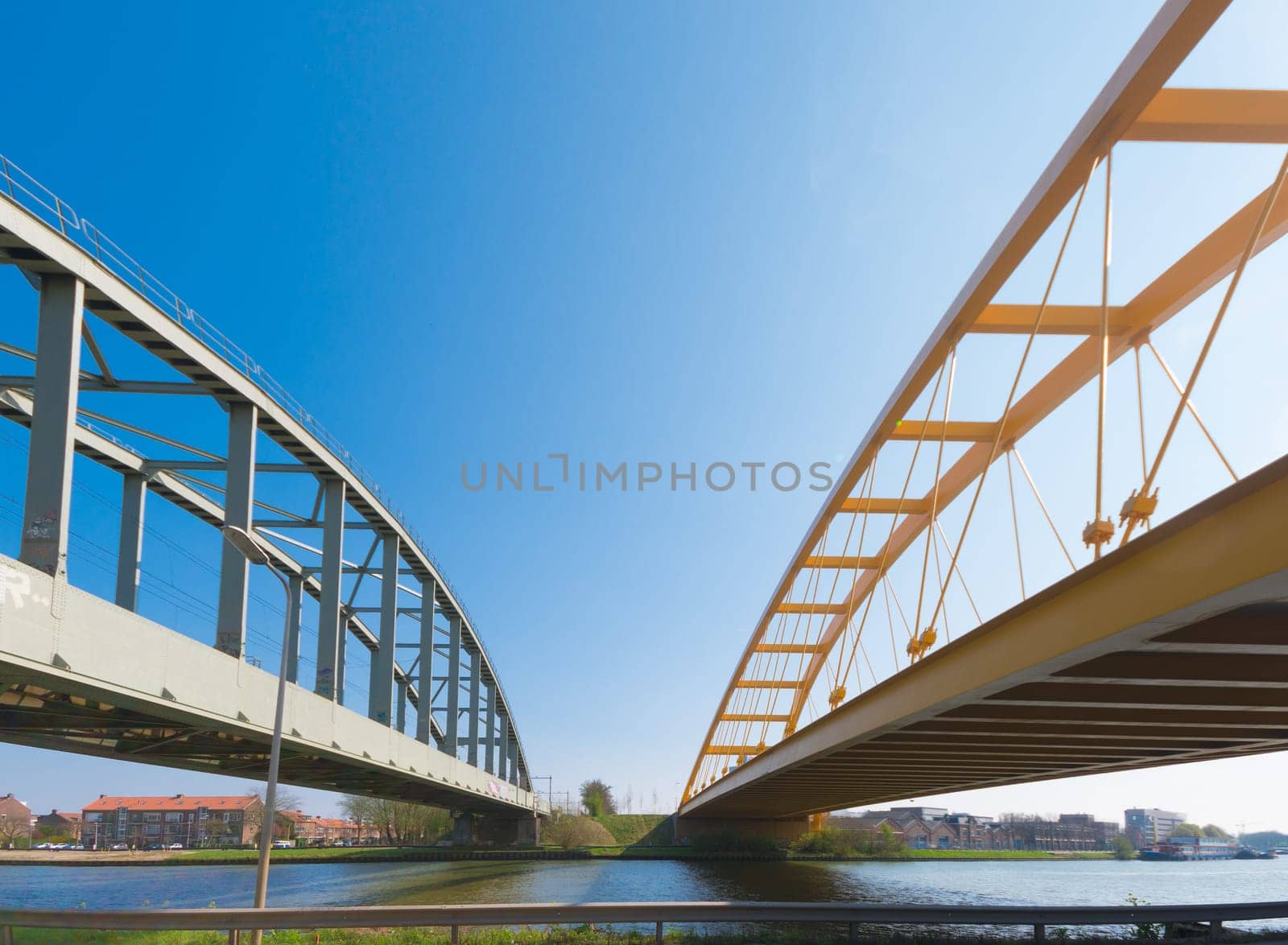railroad bridge and yellow arch bridge in Utrecht, netherlands. The yellow Hogeweide Bridge is a steel arch bridge over the Amsterdam-Rhine Canal