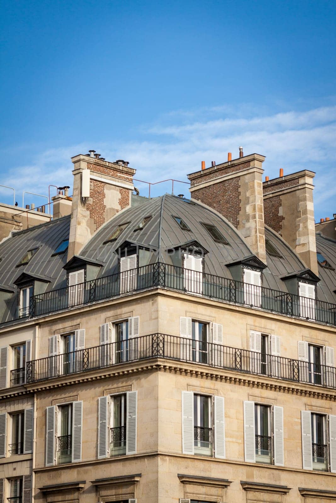 Exterior view of a Parisian townhouse in summer in front of a blue sky