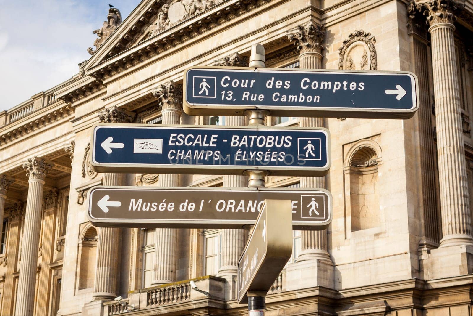 Street signs for pedestrians in downtown Paris with blue skies and buildings in the back