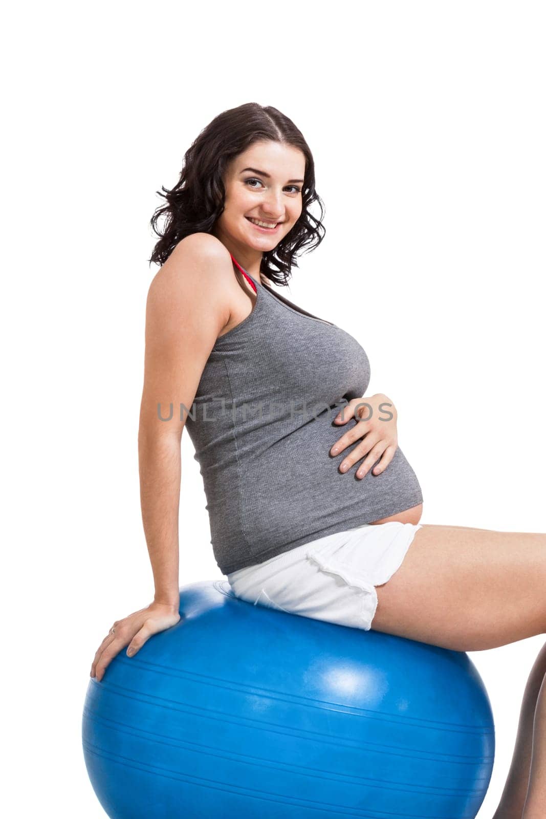 Attractive pregnant woman on a blue gymnastics ball to prepare for the brew