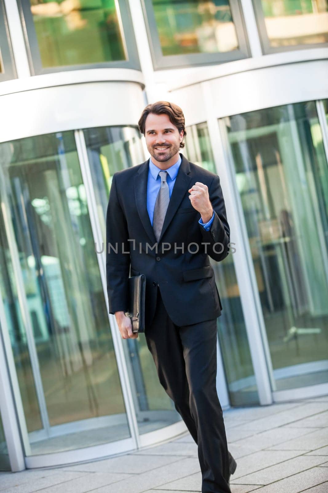 Attractive young businessman cheering in front of a business building in the summer
