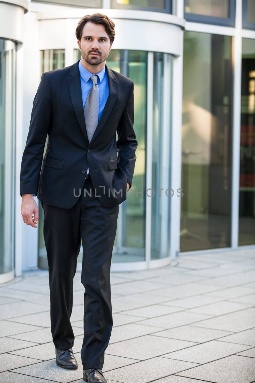 Young trendy businessman in front of a business building successfully with beard and dark hair
