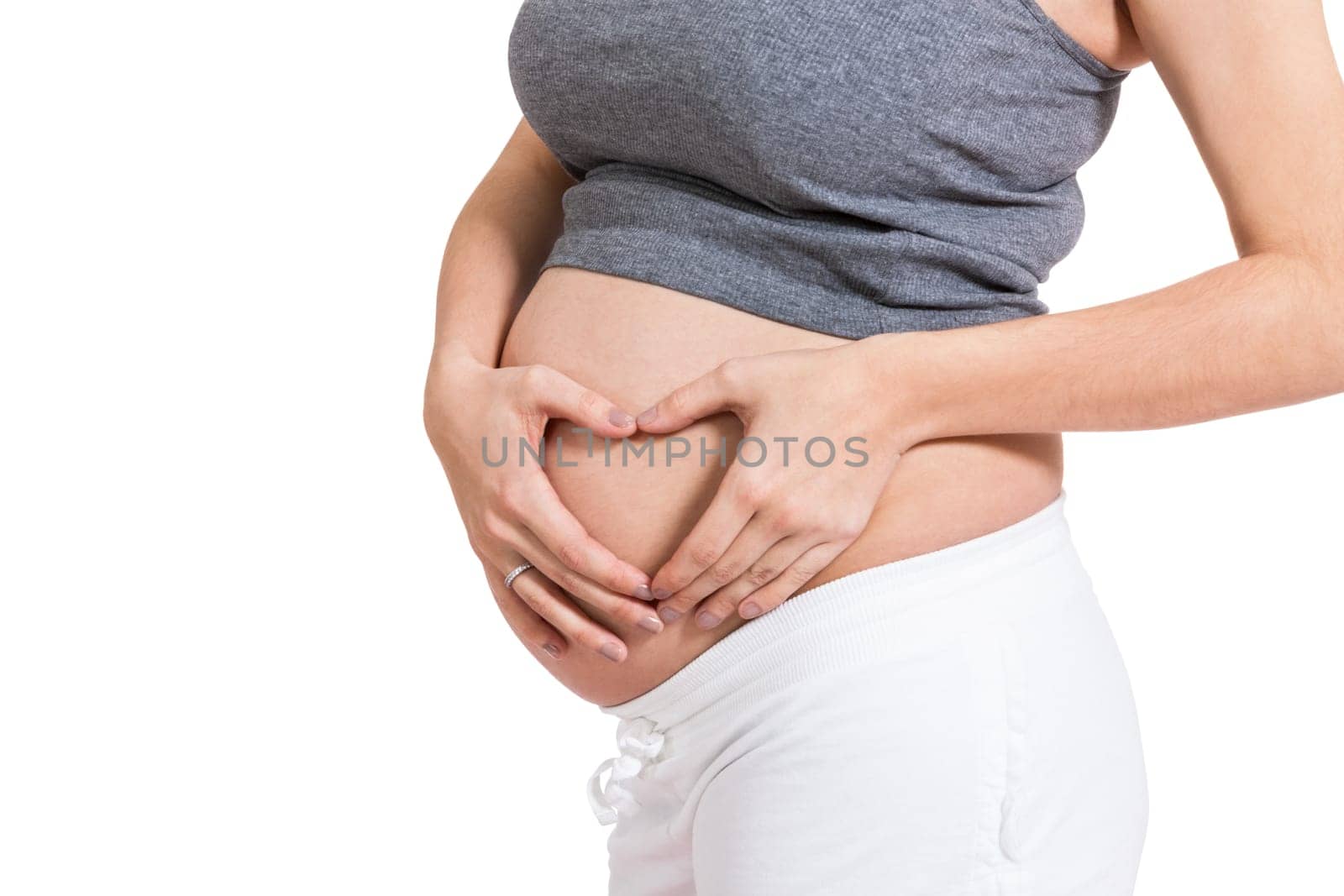 Young pregnant woman forms a heart in front of her baby belly isolated against white background with her hands