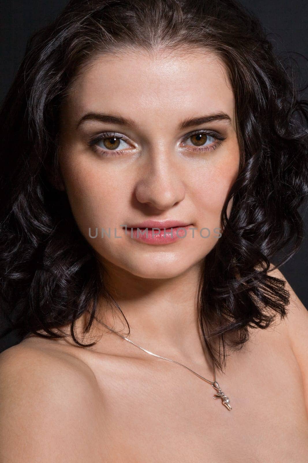 Young attractive woman with freckles in portrait against a black background