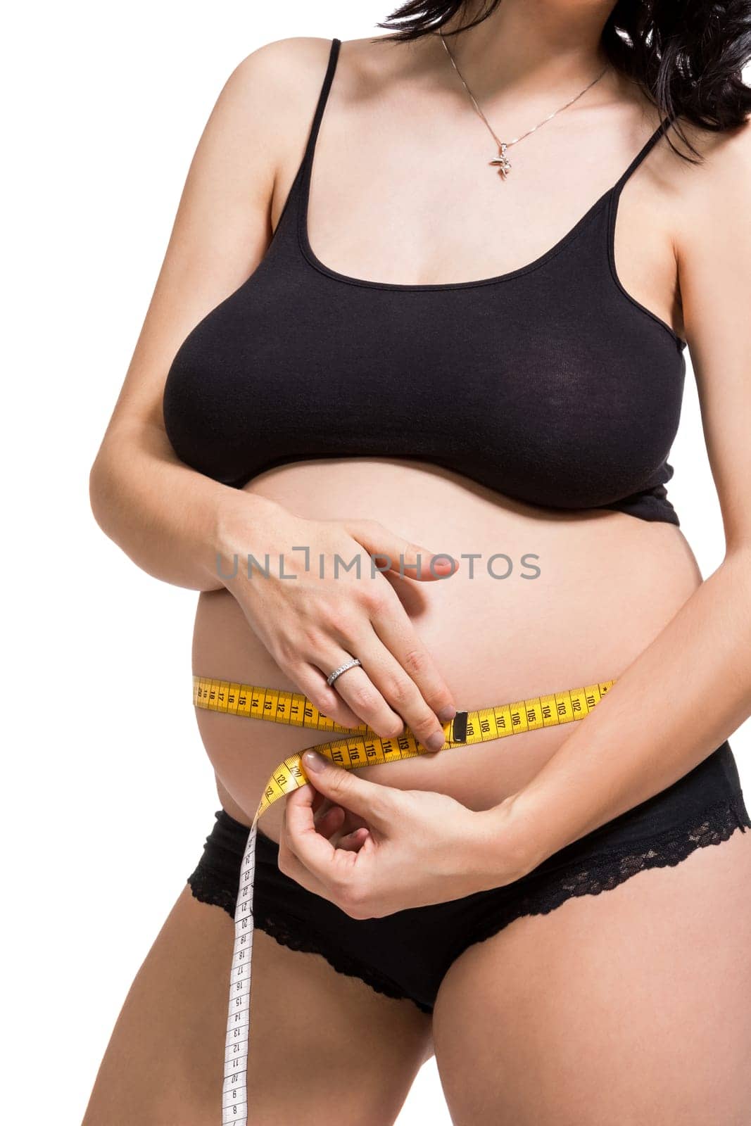 Pregnant woman with a measuring tape measures her girth on her abdomen isolated against a white background