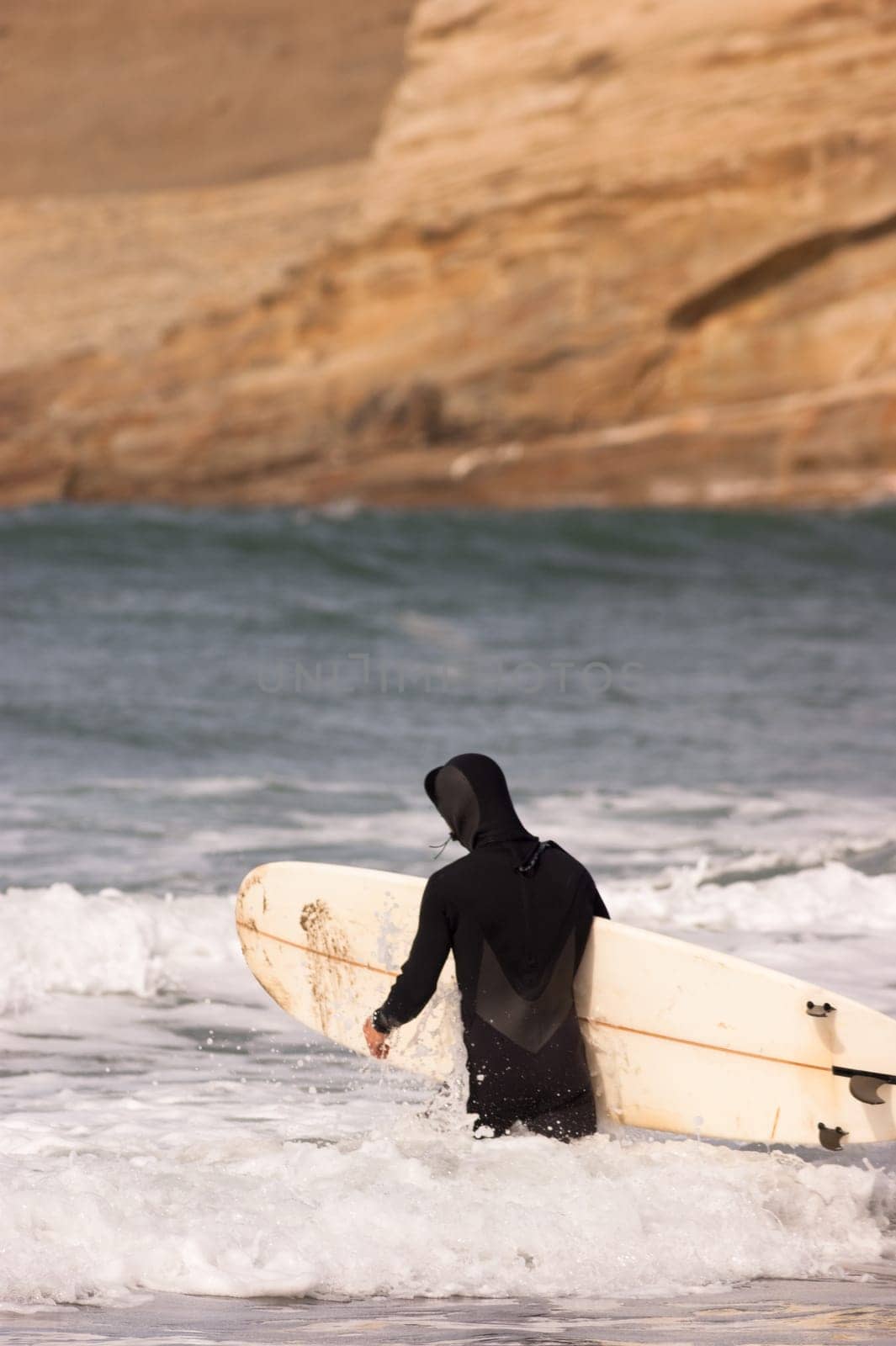 Adult male heads out to sea for a surfing session