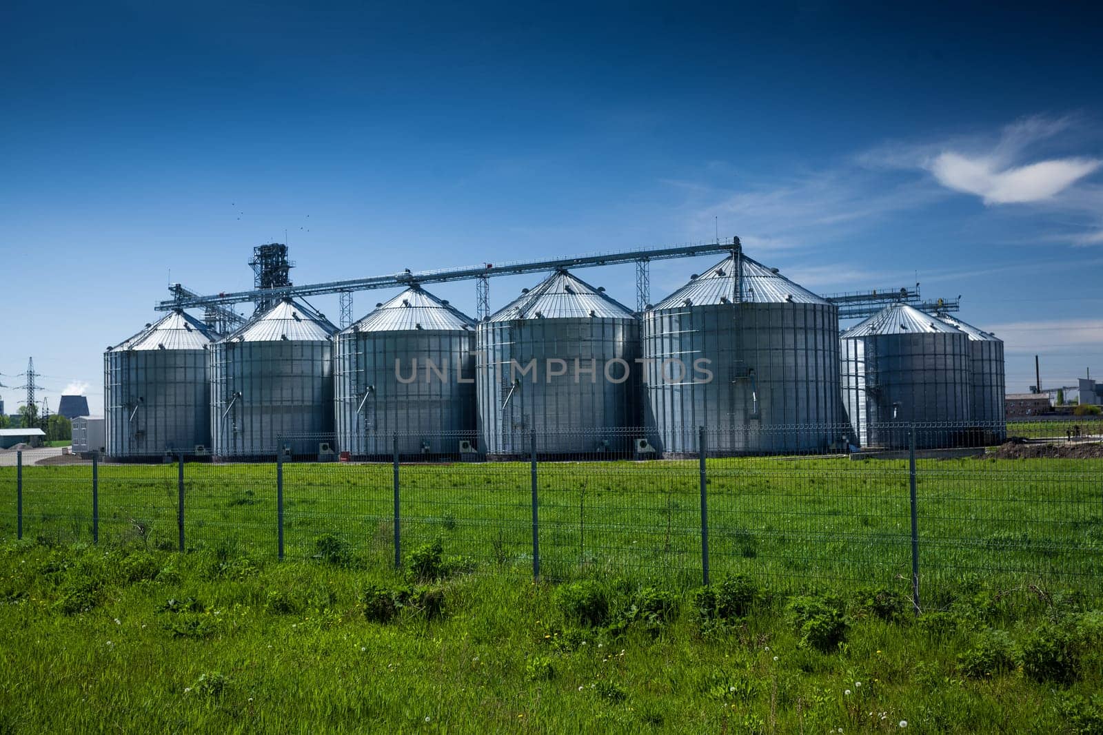 Landscape of grain elevator at field against deep blue sky