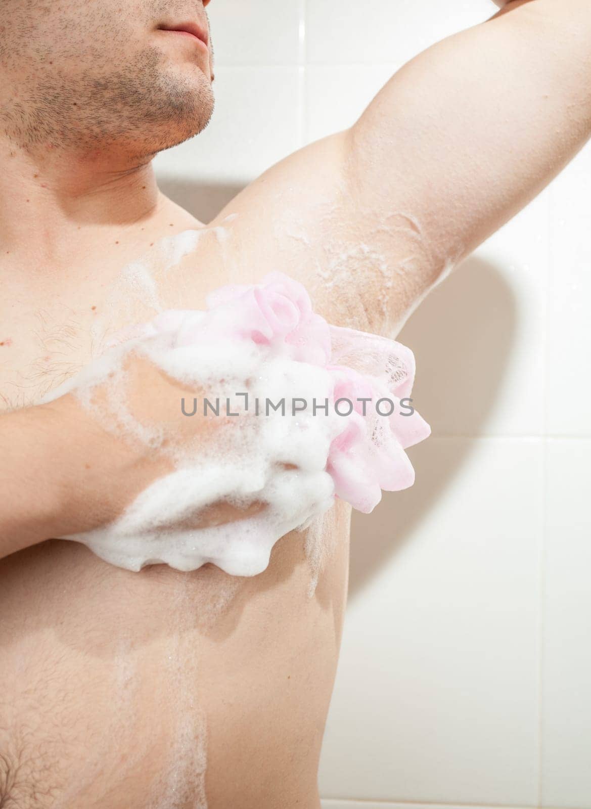 Closeup photo of young man washing armpit with sponge