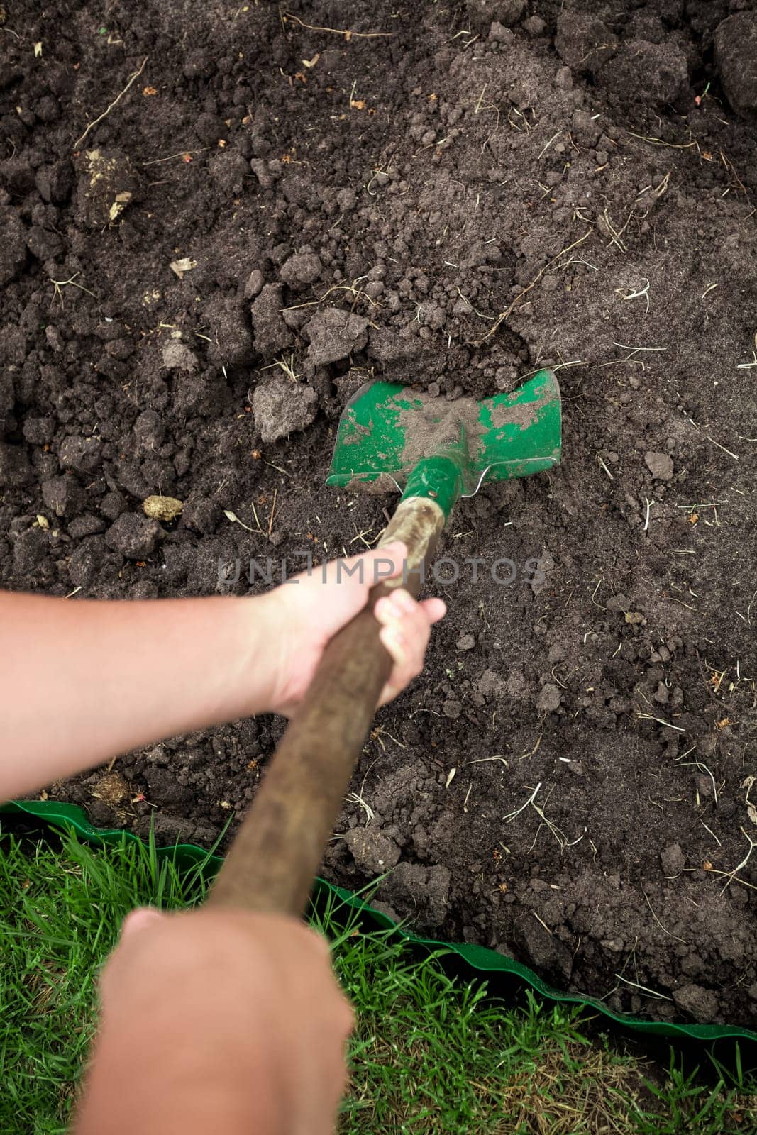 Closeup photo of gardener digging soil with shovel