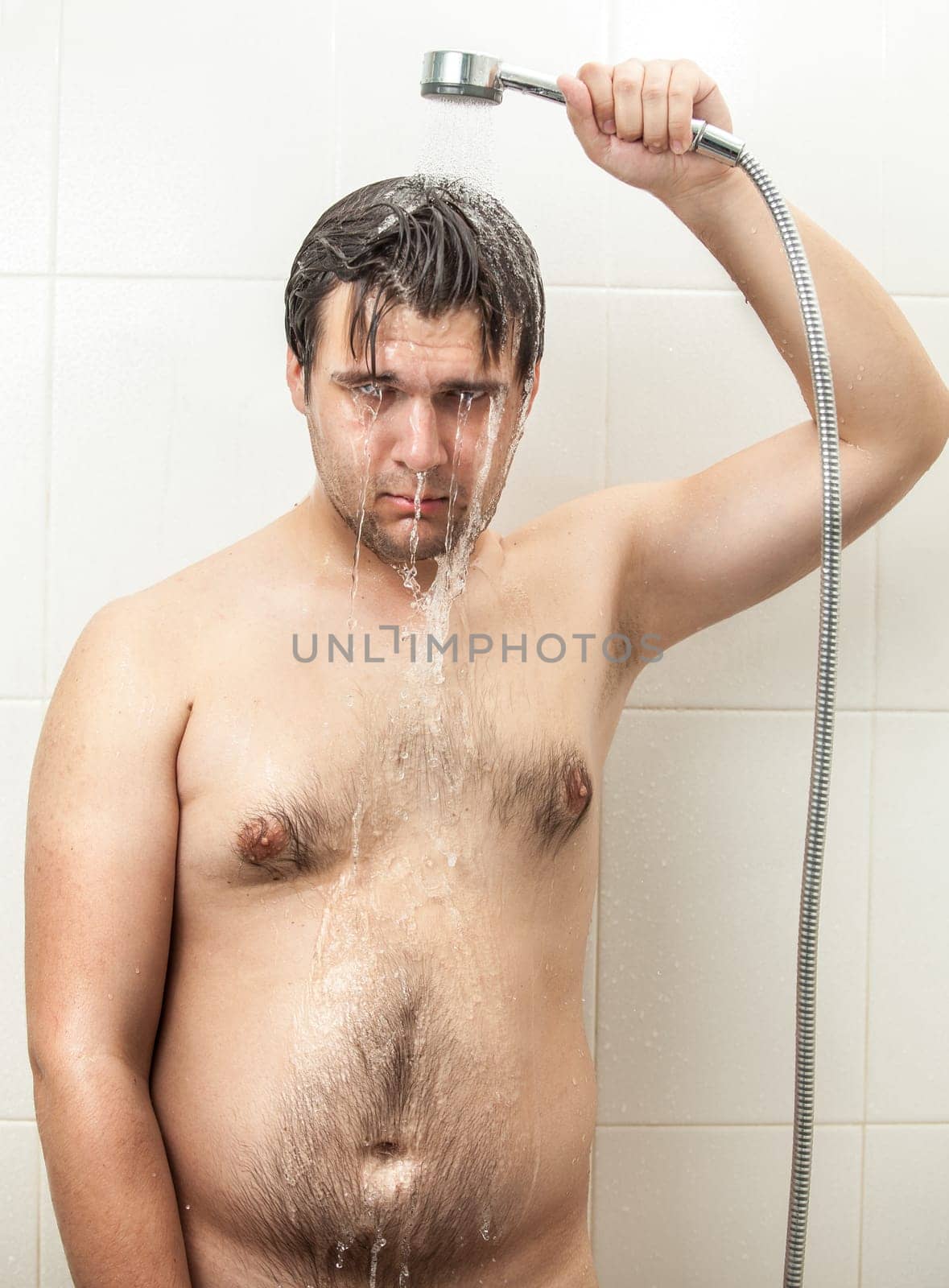 Portrait of depressed fat hairy man having shower