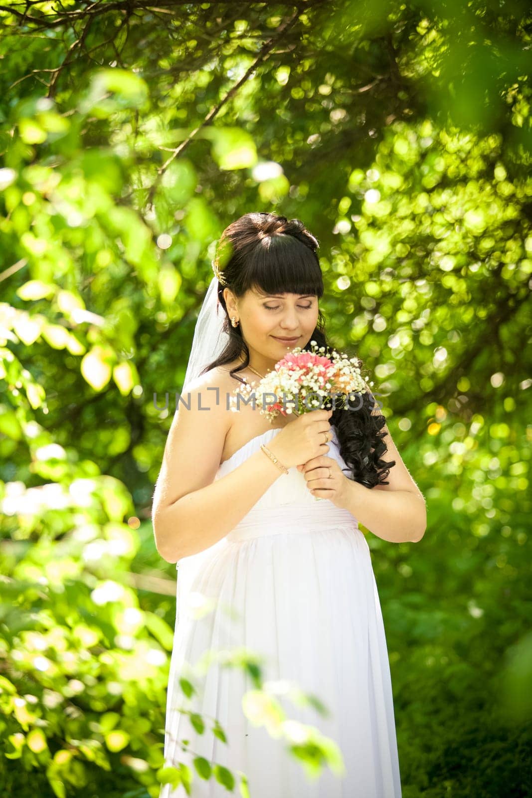 Portrait of smiling cute bride smelling bouquet at park