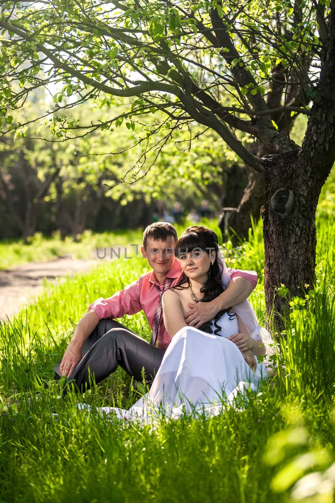 Portrait of newly married couple hugging under tree at alley