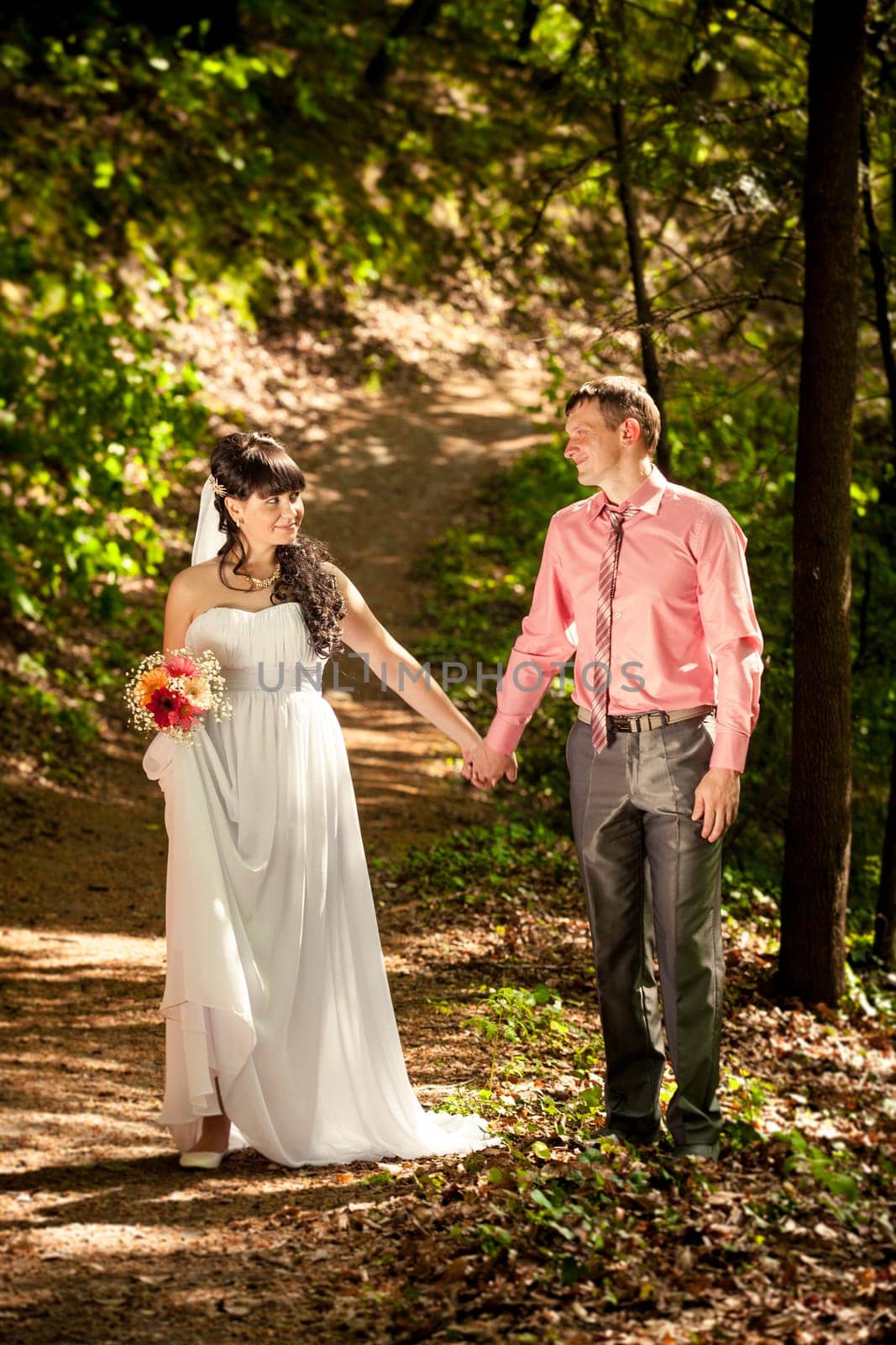 Just married couple holding hands and walking at park