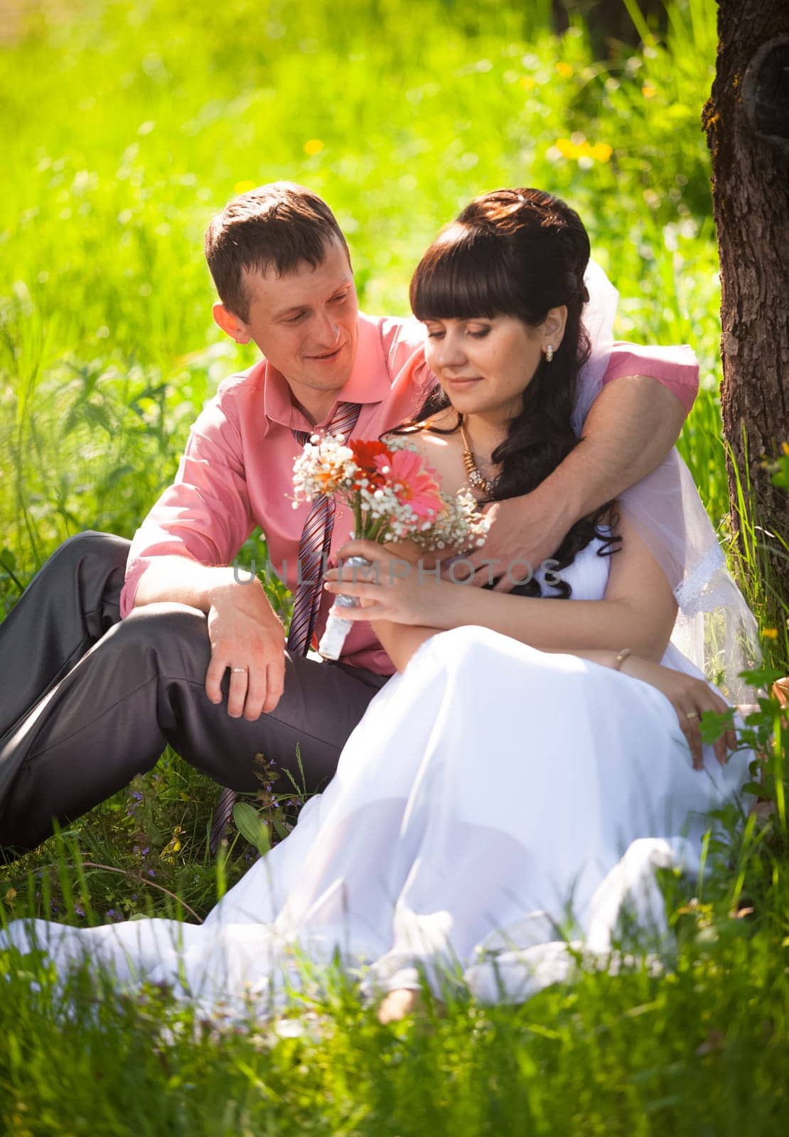 Portrait of young groom presenting flower to bride under tree at park