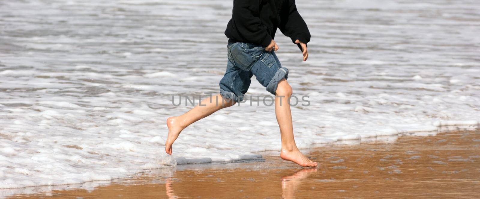 Panoramic shot of boy playing in the ocean surf