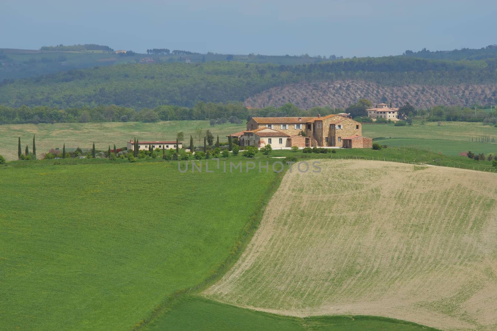 View of Tuscany landscape with farm surrounded by fields.