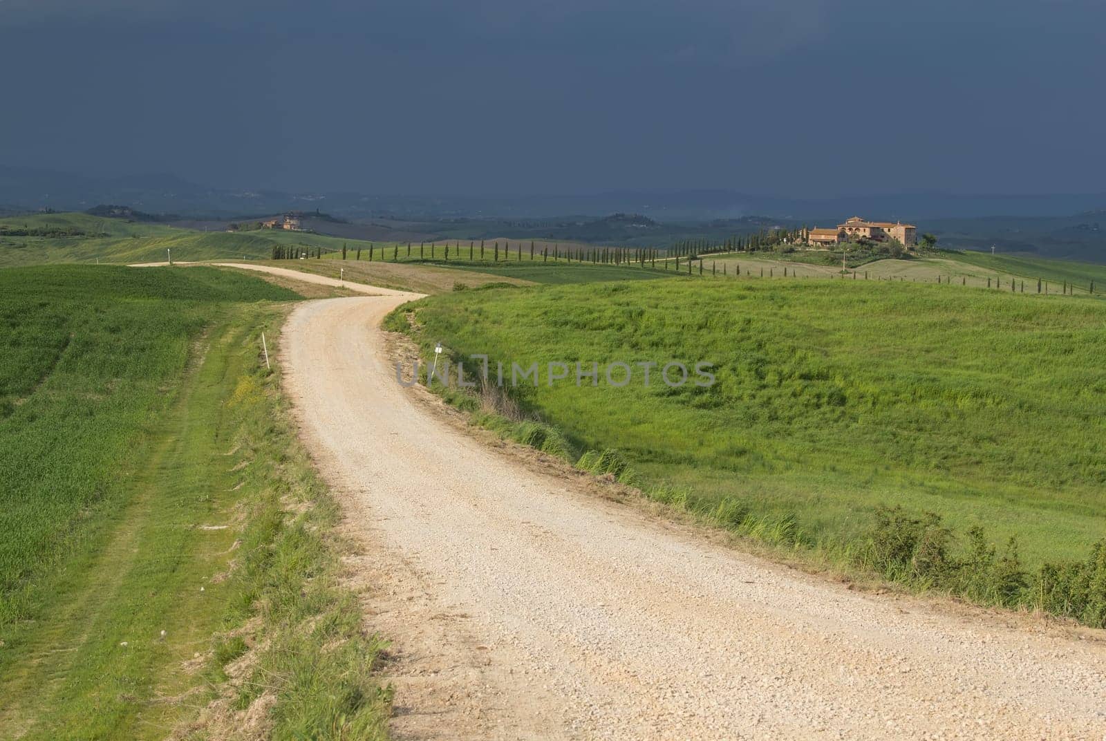 Dirty road in the middle of the Tuscan countryside. Storm dark sky in the background. .