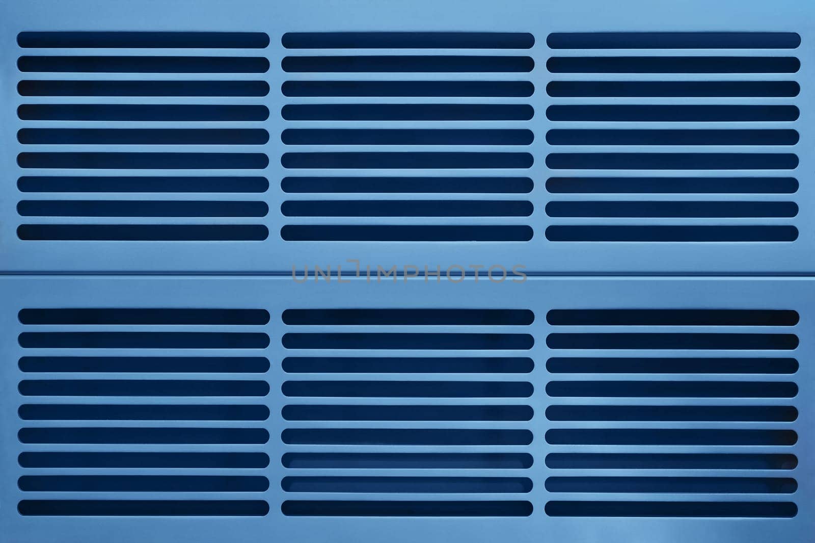 abstract industrial background made of aluminium ventilation grilles in blue light