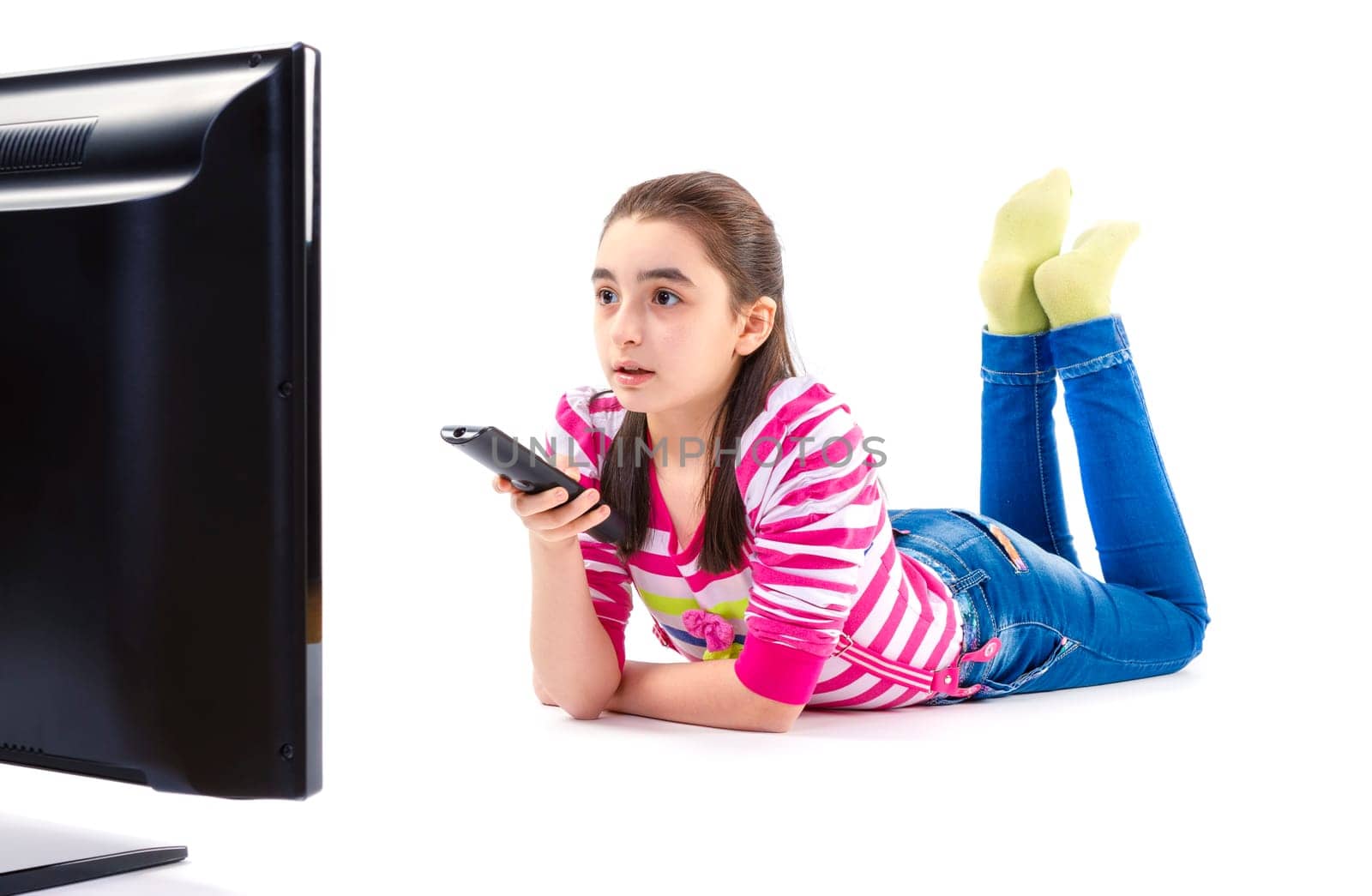 Little girl with remote control laying down and watching tv