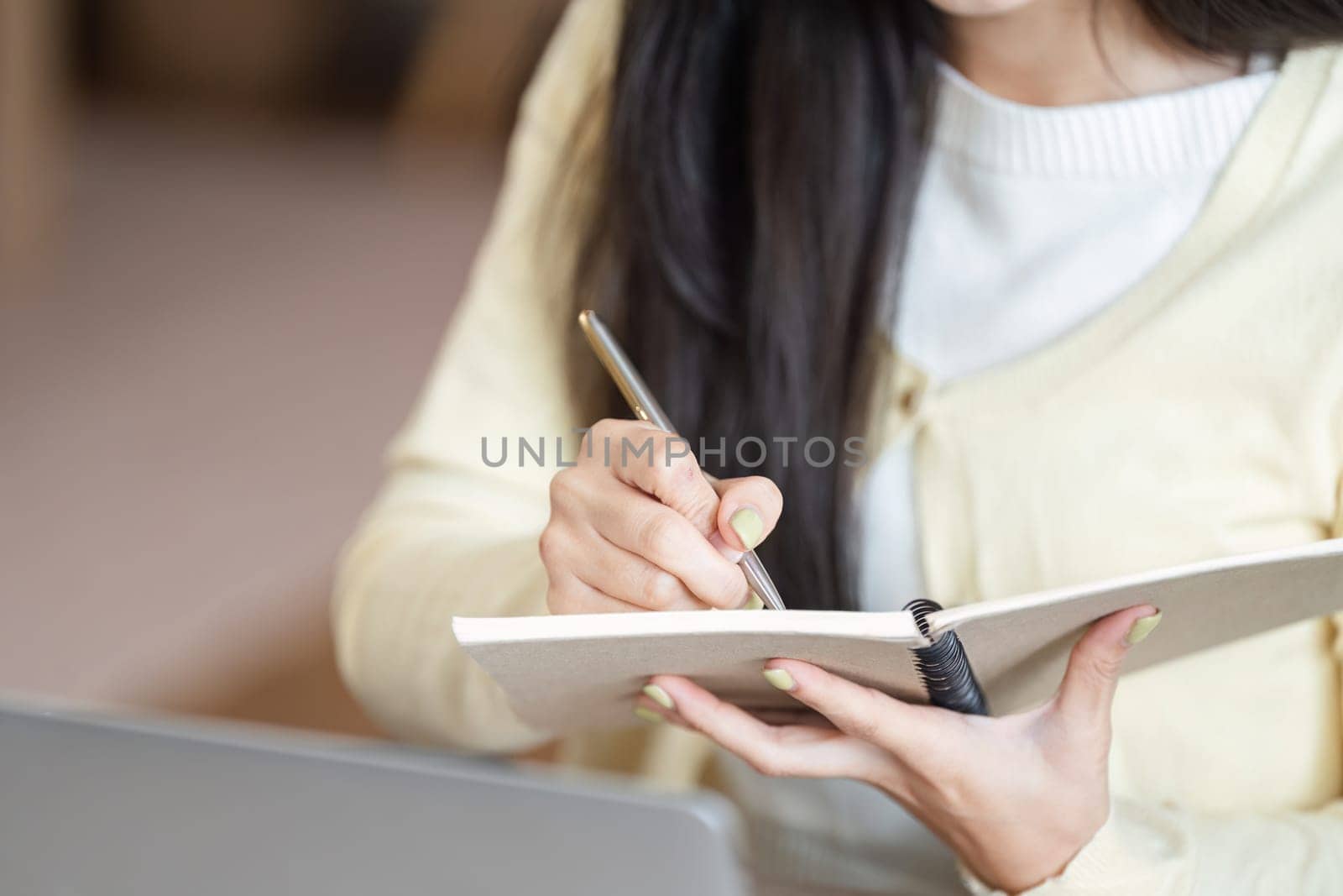 A freelance businesswoman writes notes while brainstorming ideas in her home office, showcasing creativity and planning.