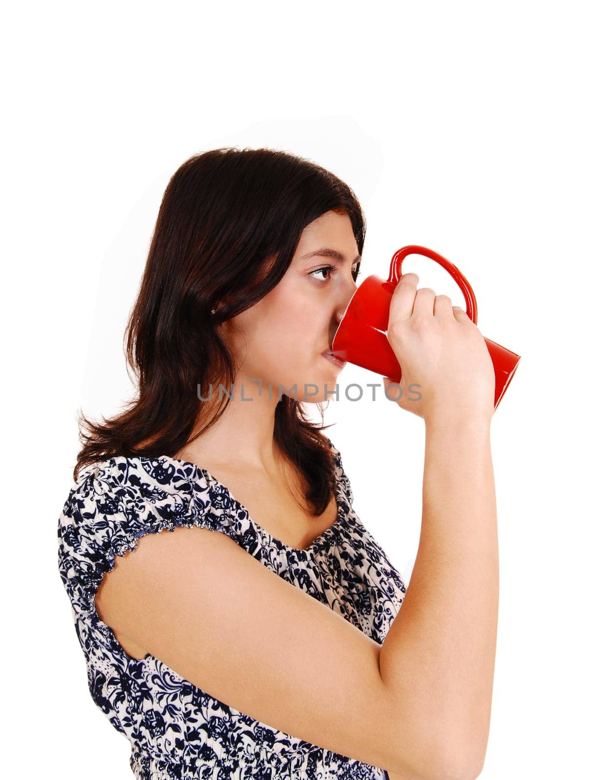 A young brunette woman in a dress drinking coffee from a red mug,.isolated on white background..