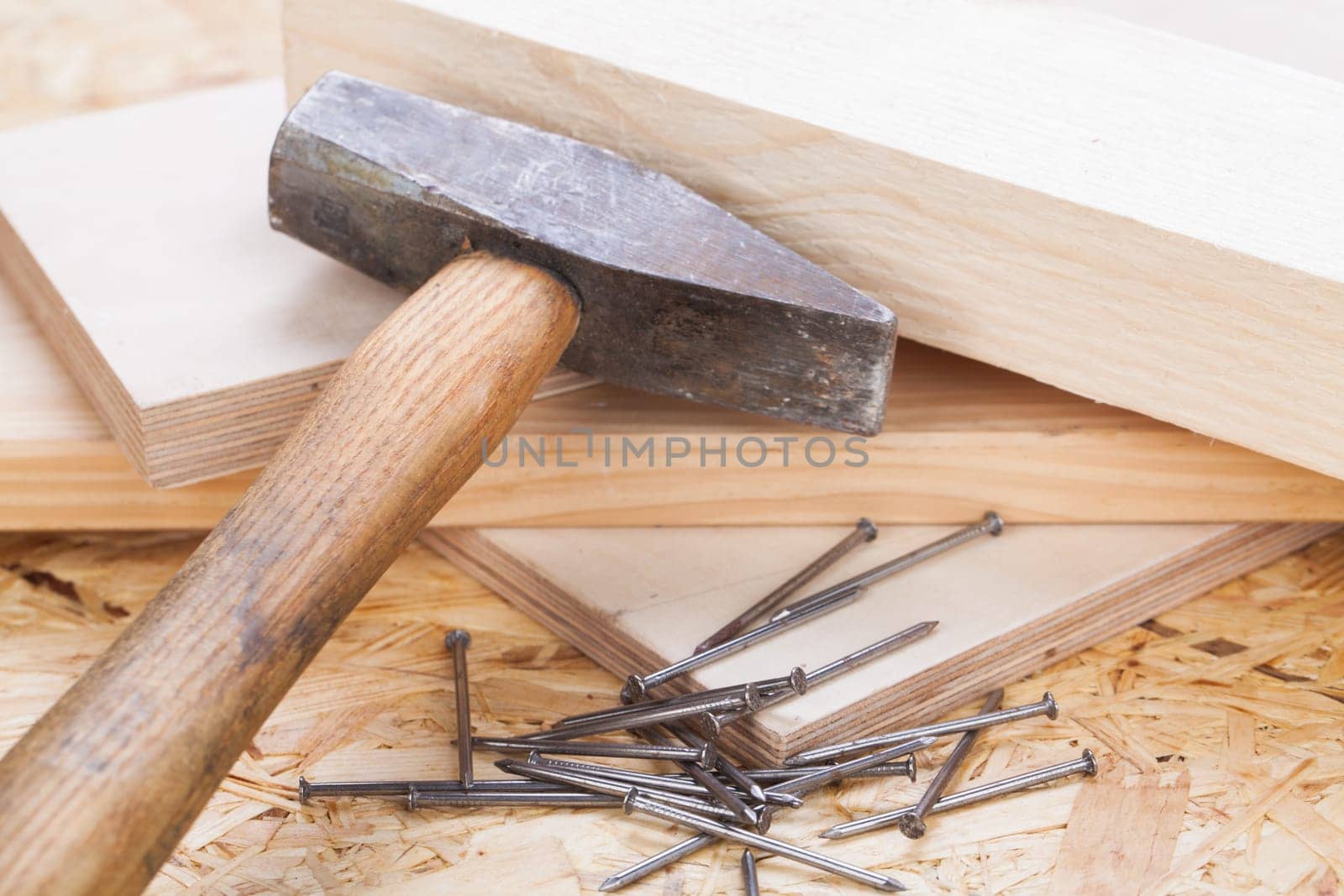 Hammer with nails on a wooden board in a workshop of a do-it-yourselfer
