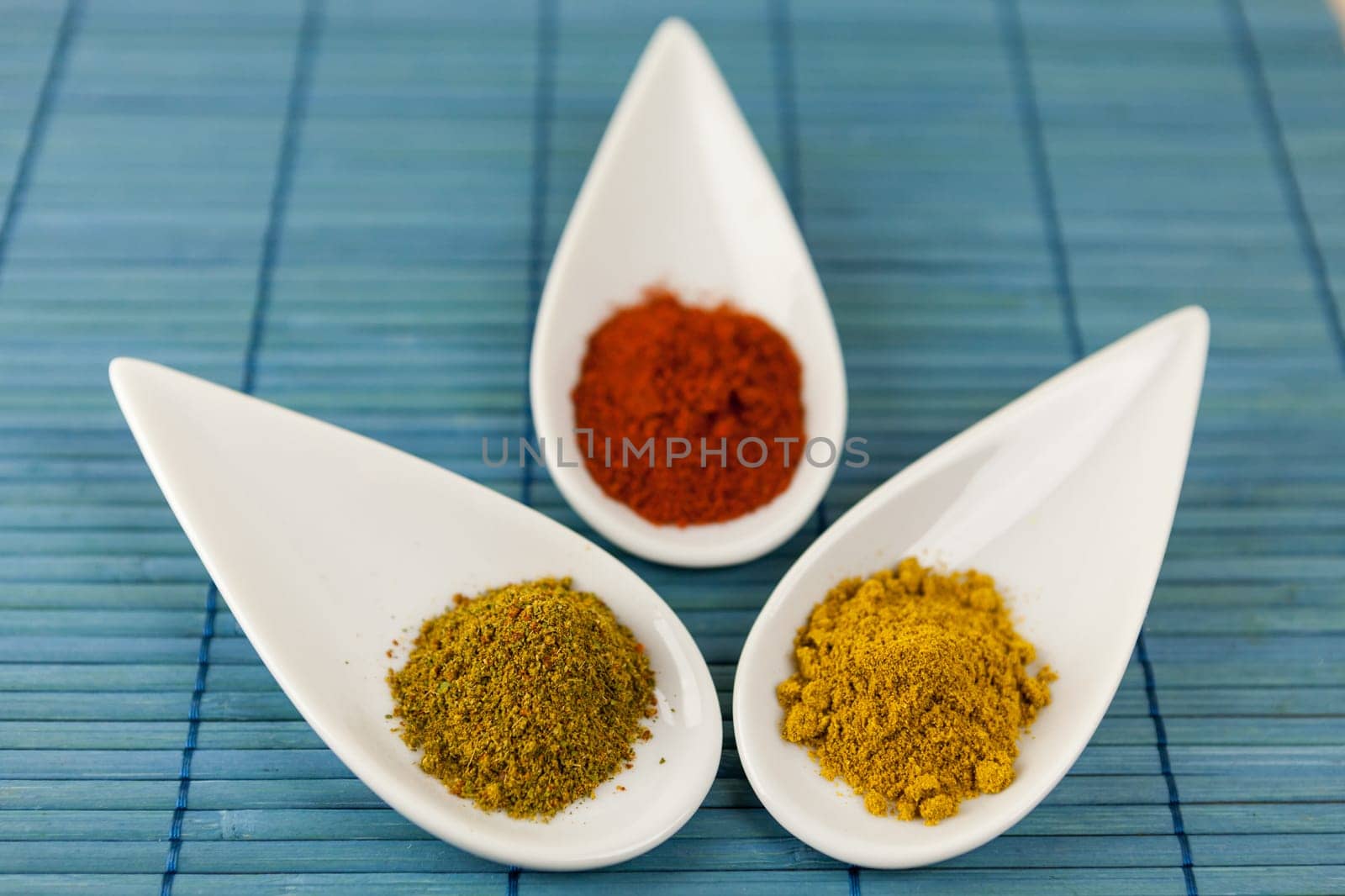 dried spices in porcelain bowls on a blue background