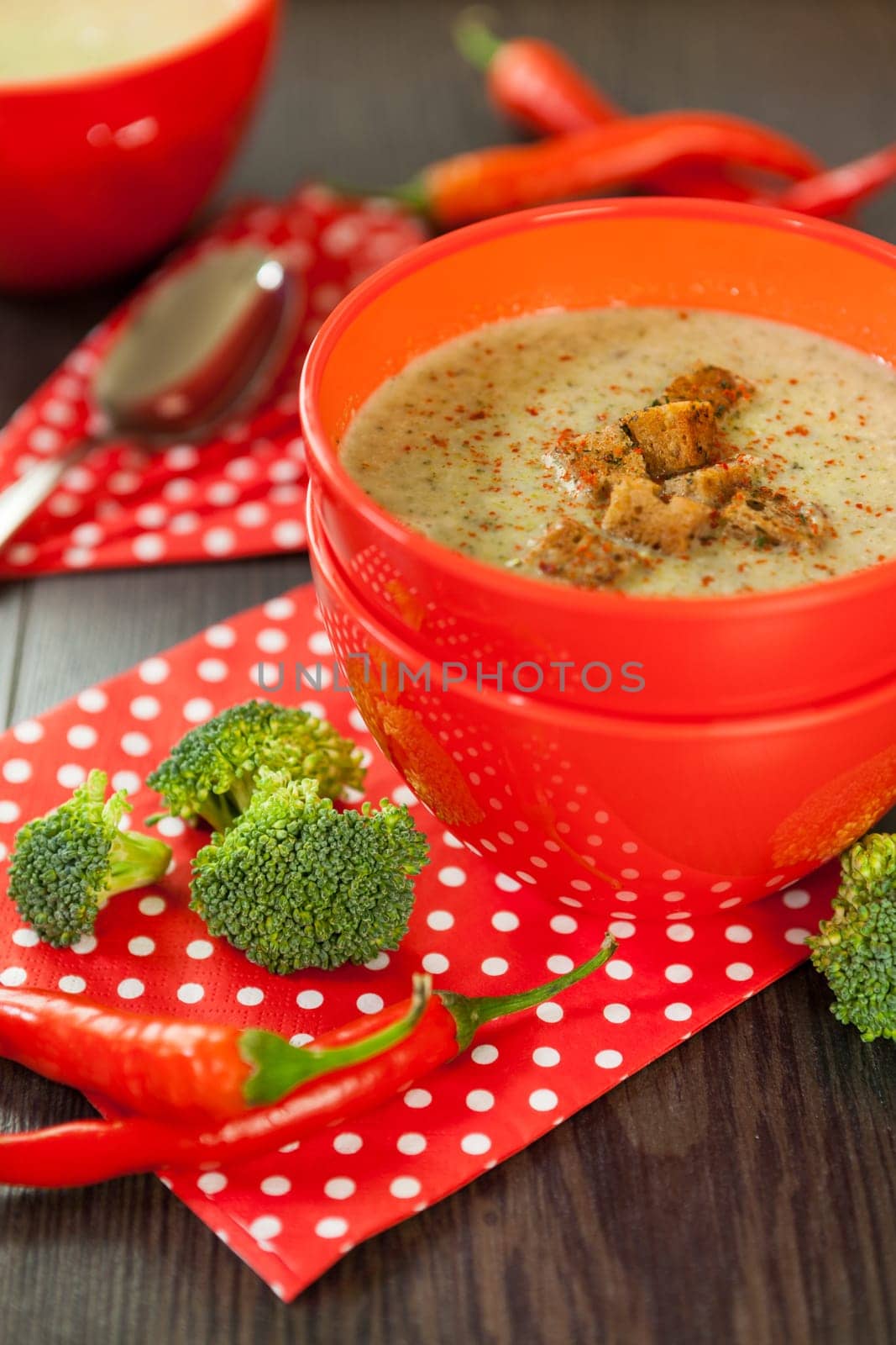 Soup bowl with broccoli soup with fresh pepper and chilli close-up on a wooden table