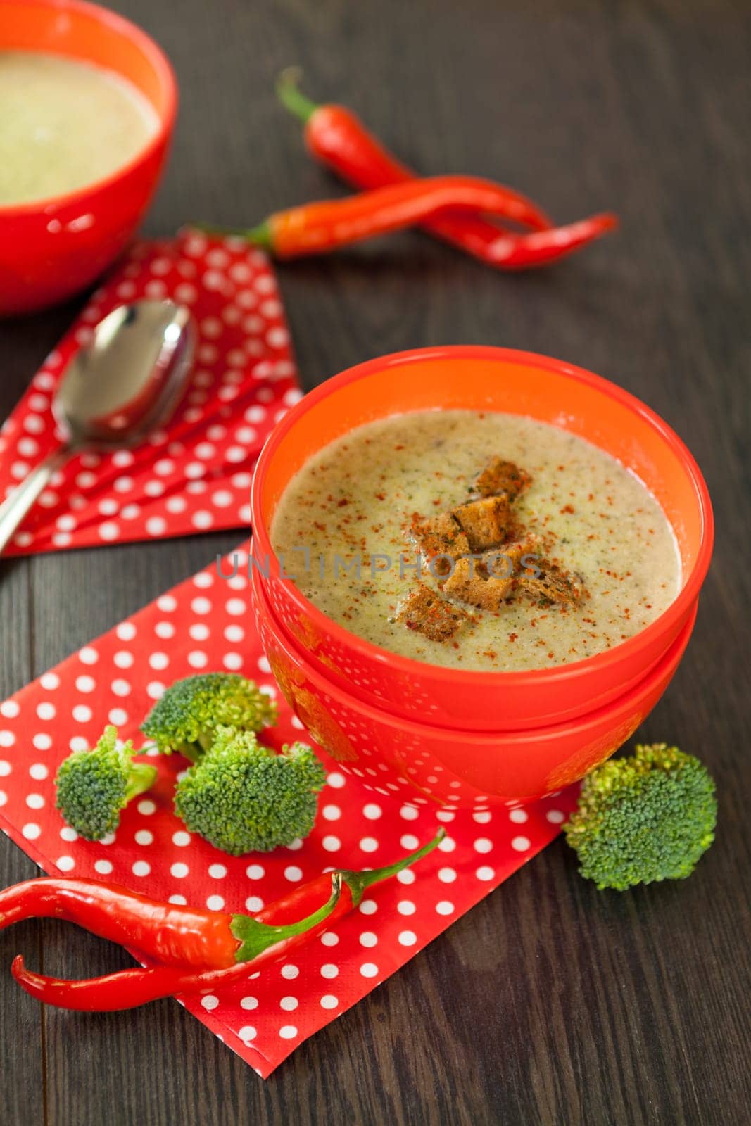 Soup bowl with broccoli soup with fresh pepper and chilli close-up on a wooden table