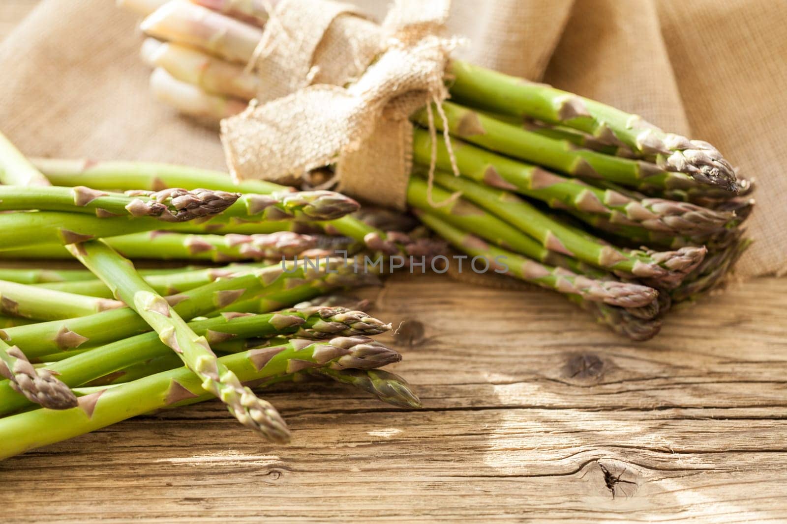 Fresh healthy green asparagus as a close-up on a wooden table in sunlight
