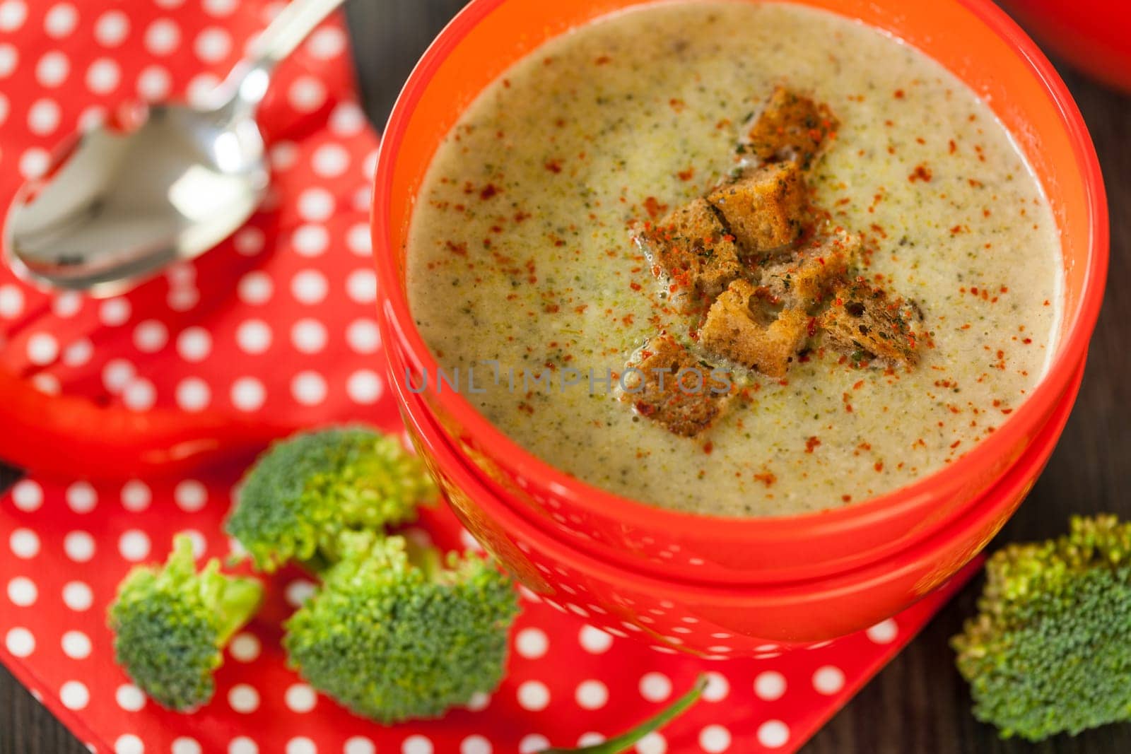 Soup bowl with broccoli soup with fresh pepper and chilli close-up on a wooden table