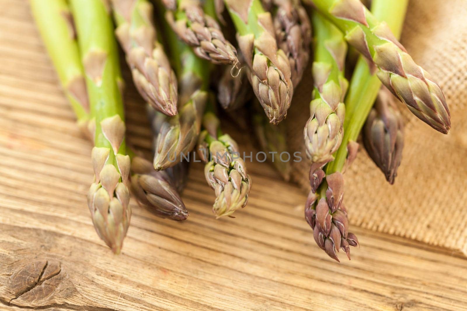 Fresh healthy green asparagus as a close-up on a wooden table in sunlight
