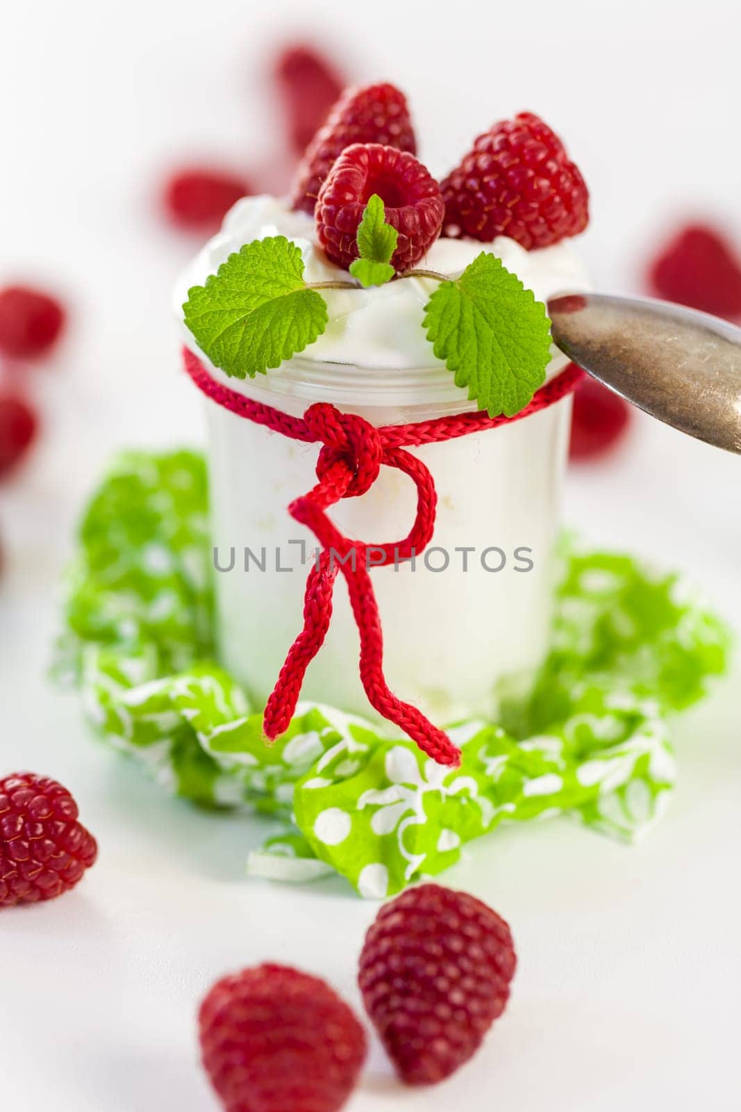 Fresh yoghurt with raspberries in a glass insulated on a white background