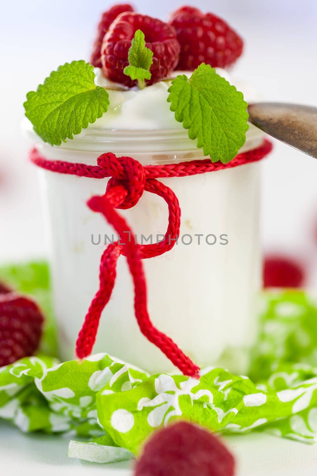 Fresh yoghurt with raspberries in a glass insulated on a white background
