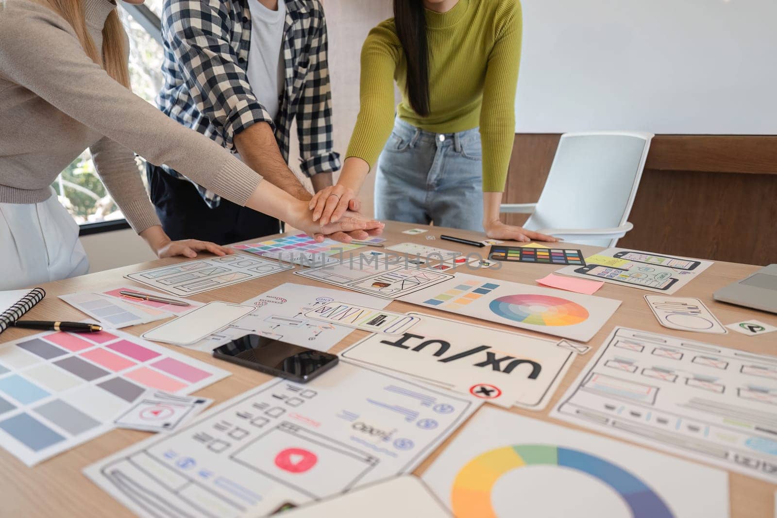 A diverse group of professionals collaborates on a UX design project, expressing excitement and teamwork in a contemporary office setting.
