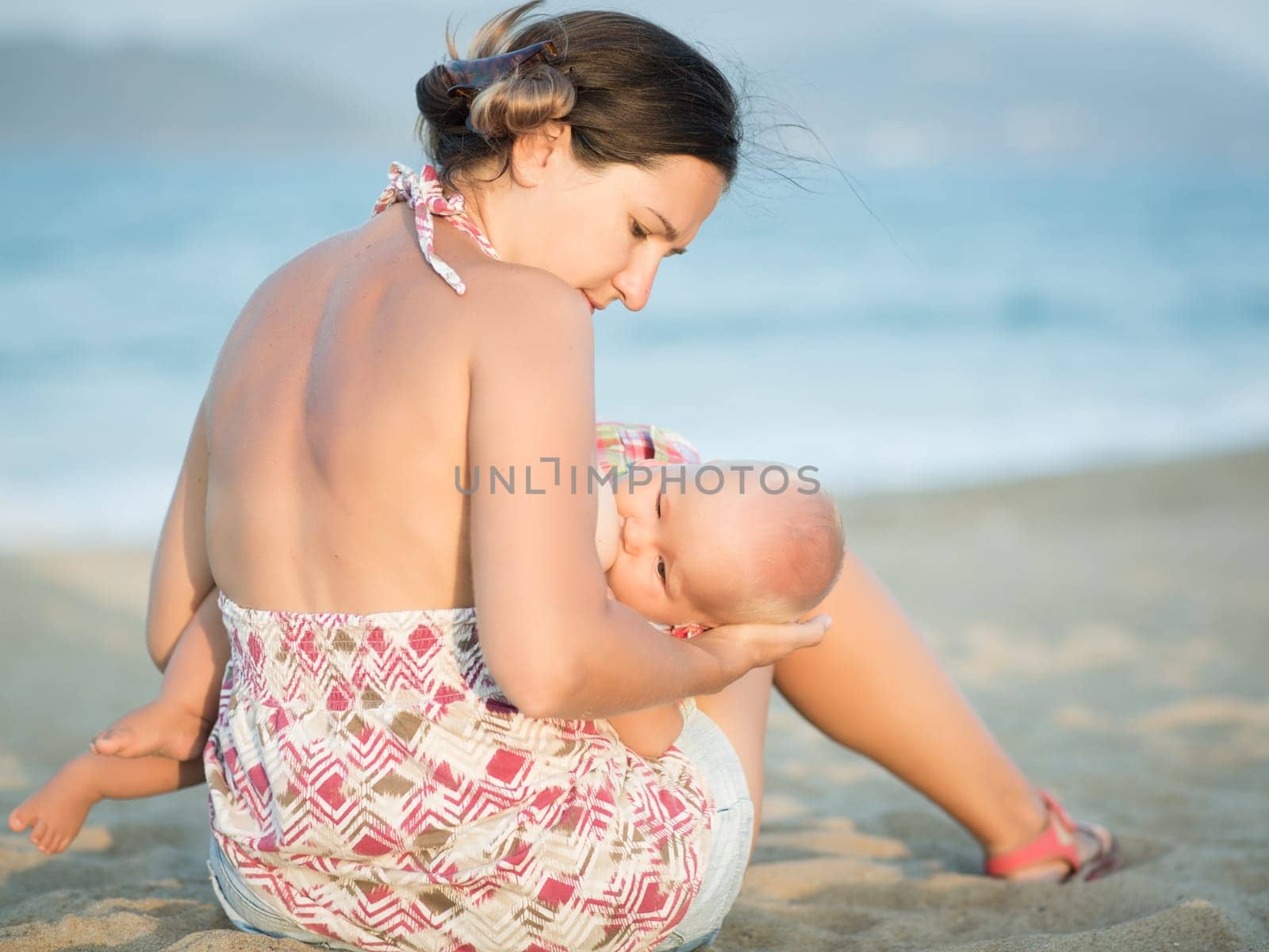 Mother breastfeeding baby on the beach