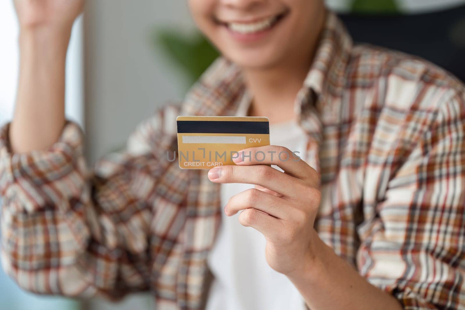 A young adult reviews bills and manages finances using a credit card and calculator at home, emphasizing financial responsibility.
